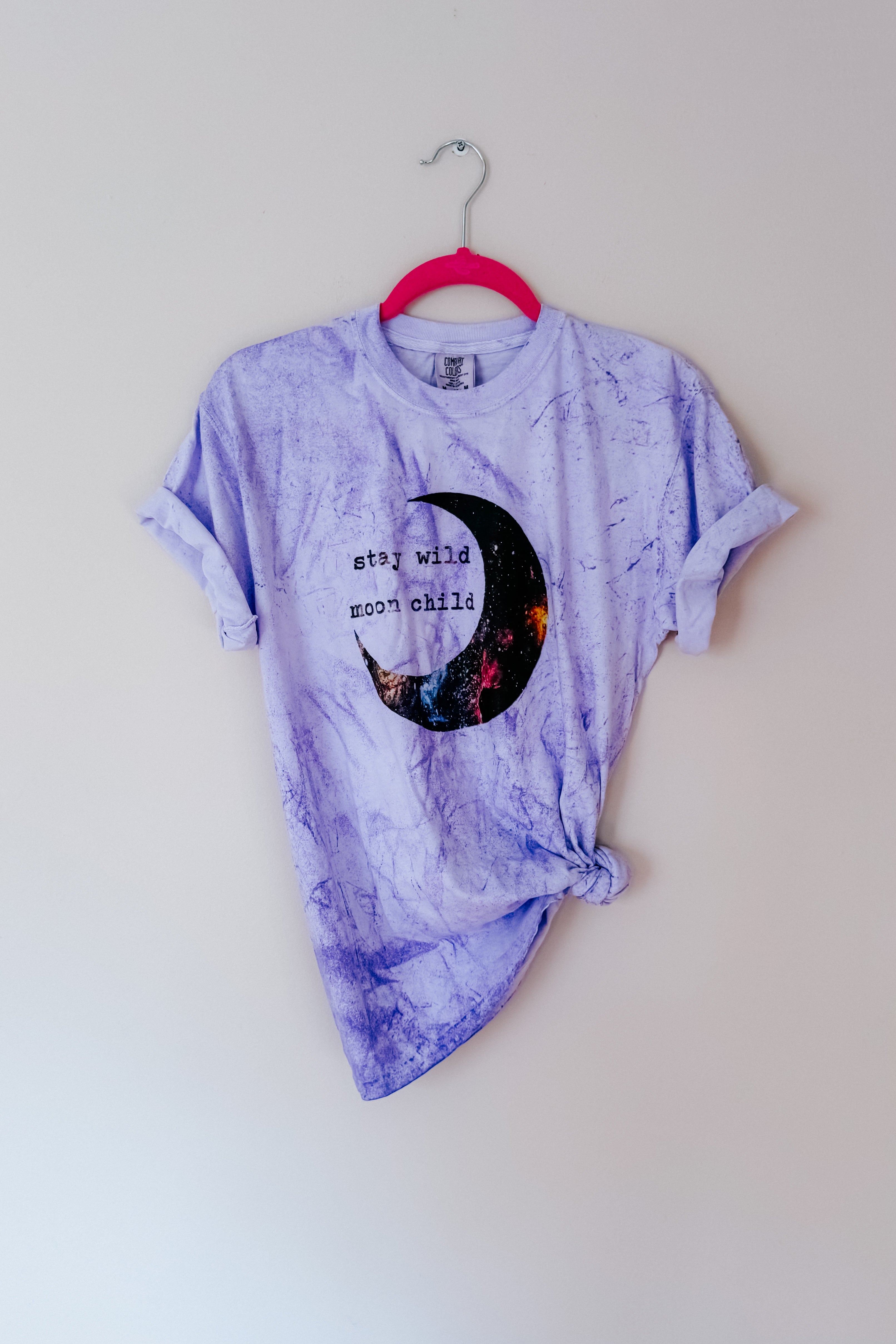 Purple tie-dye tee with rolled sleeves and cosmic crescent moon graphic reading stay wild moon child