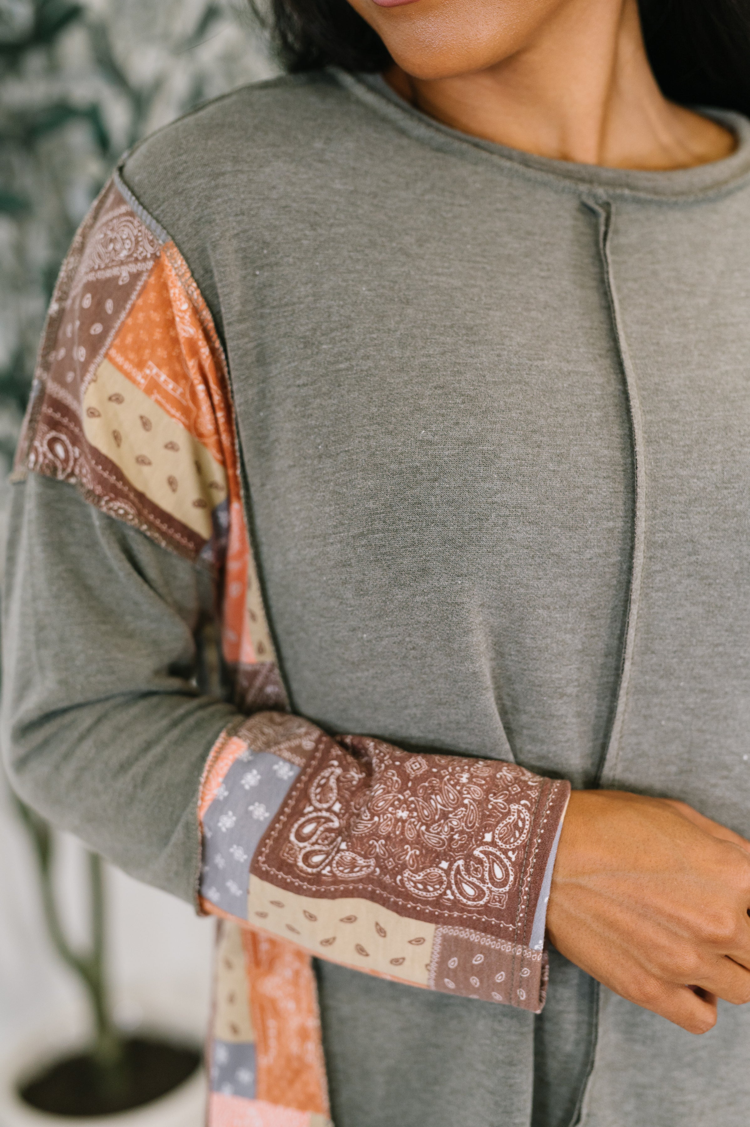 Close-up of woman wearing olive long sleeve with colorful patchwork bandana print accents on sleeves and sides