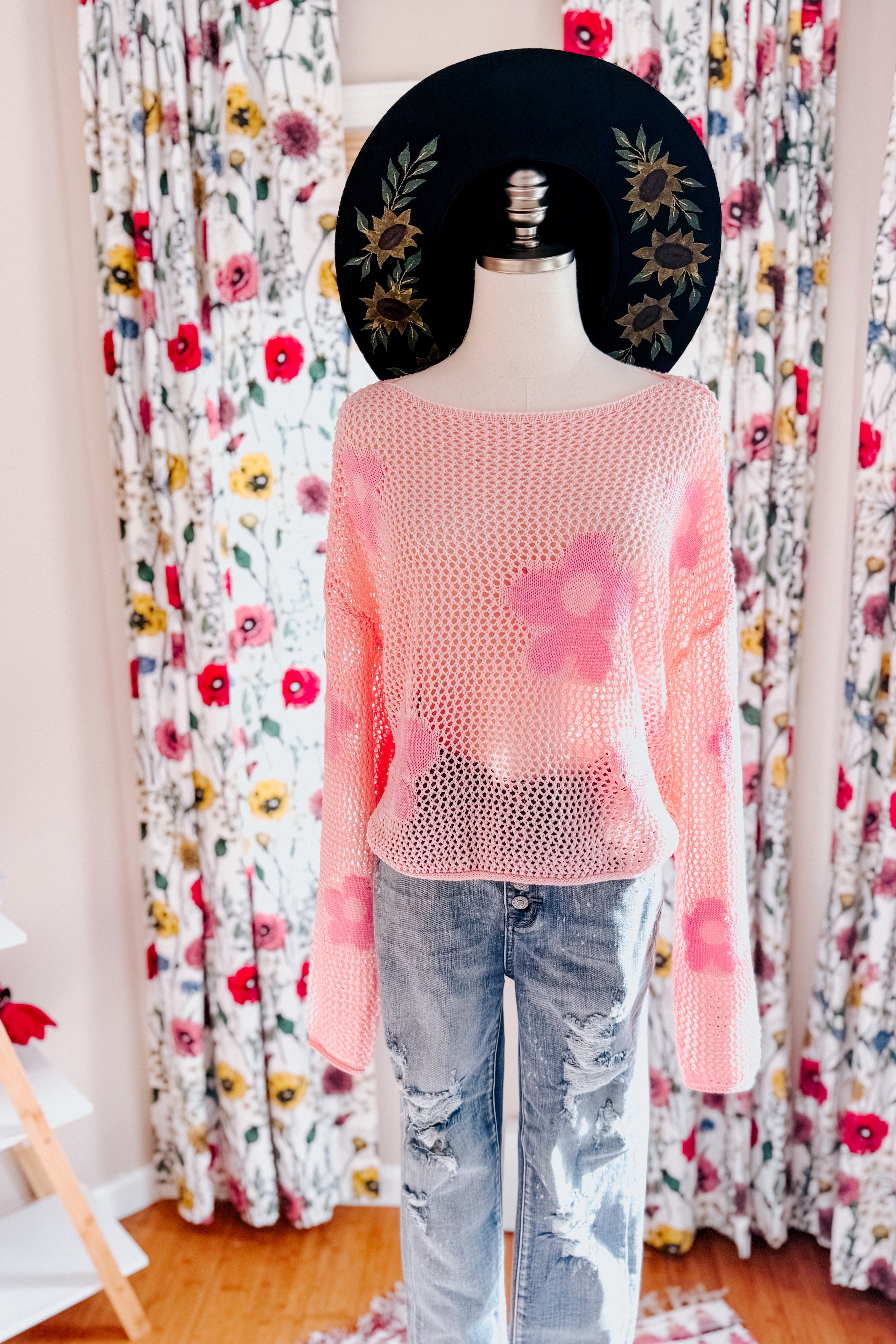 Mannequin dressed in blush pink floral mesh sweater paired with distressed light wash denim jeans indoors