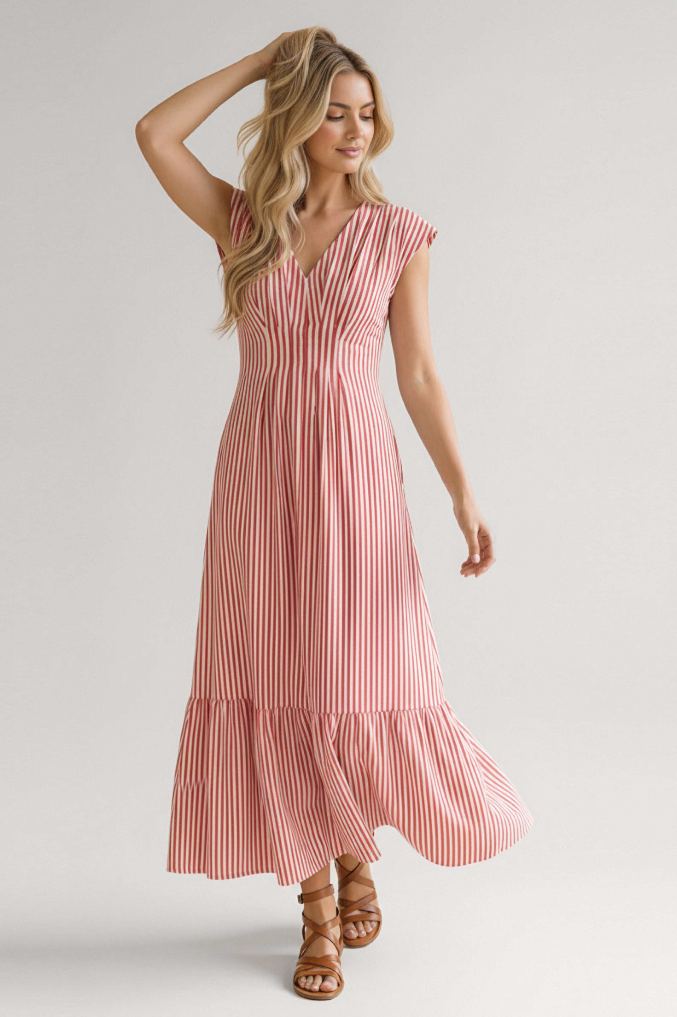 Woman in red striped tiered maxi dress with cap sleeves and v-neck paired with brown sandals against light background
