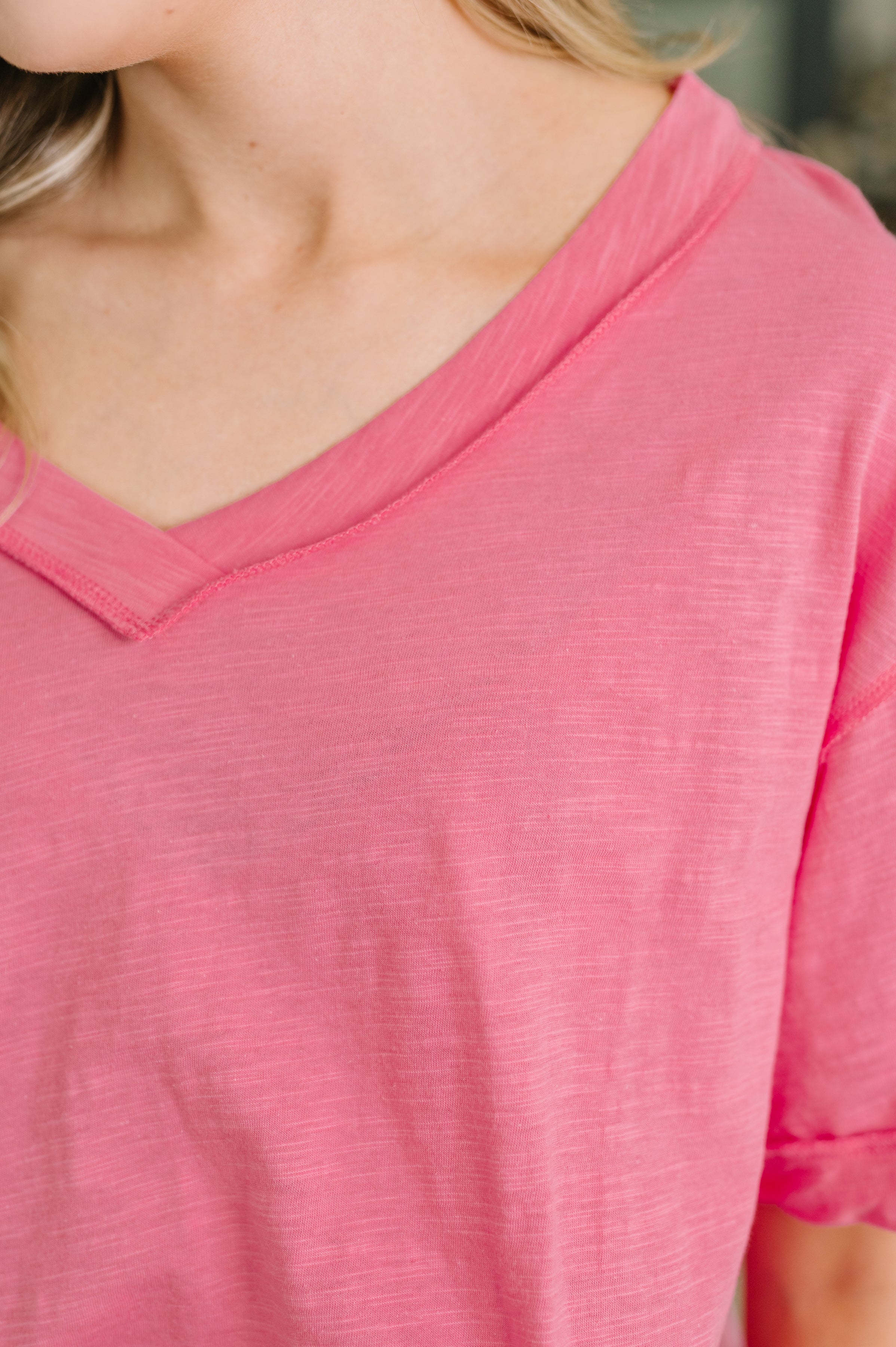 Close-up of soft pink relaxed tee with banded V-neck and subtle heathered texture on upper torso