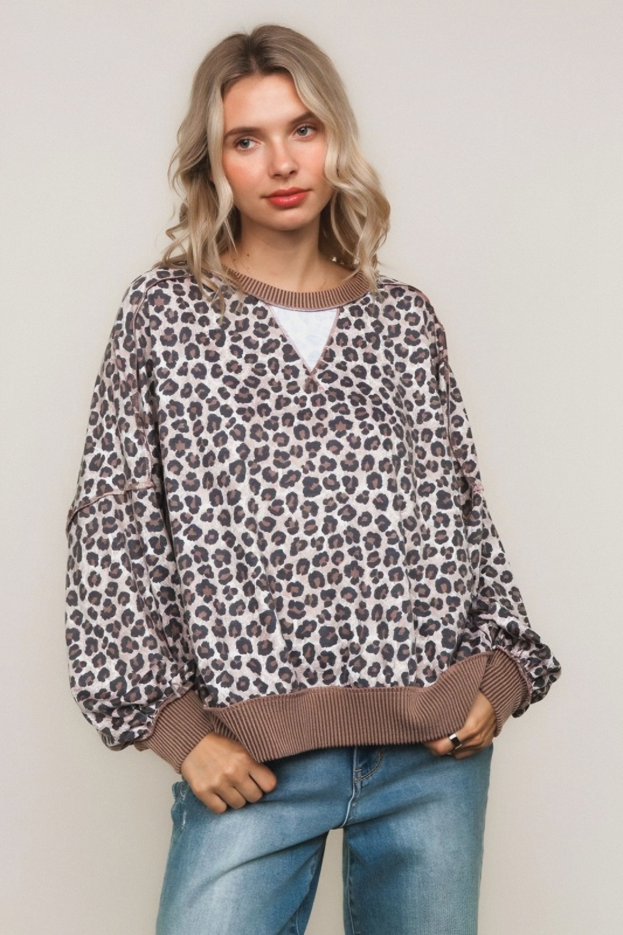 Woman with wavy blonde hair wearing a brown leopard-print pullover sweater with ribbed cuffs and hem