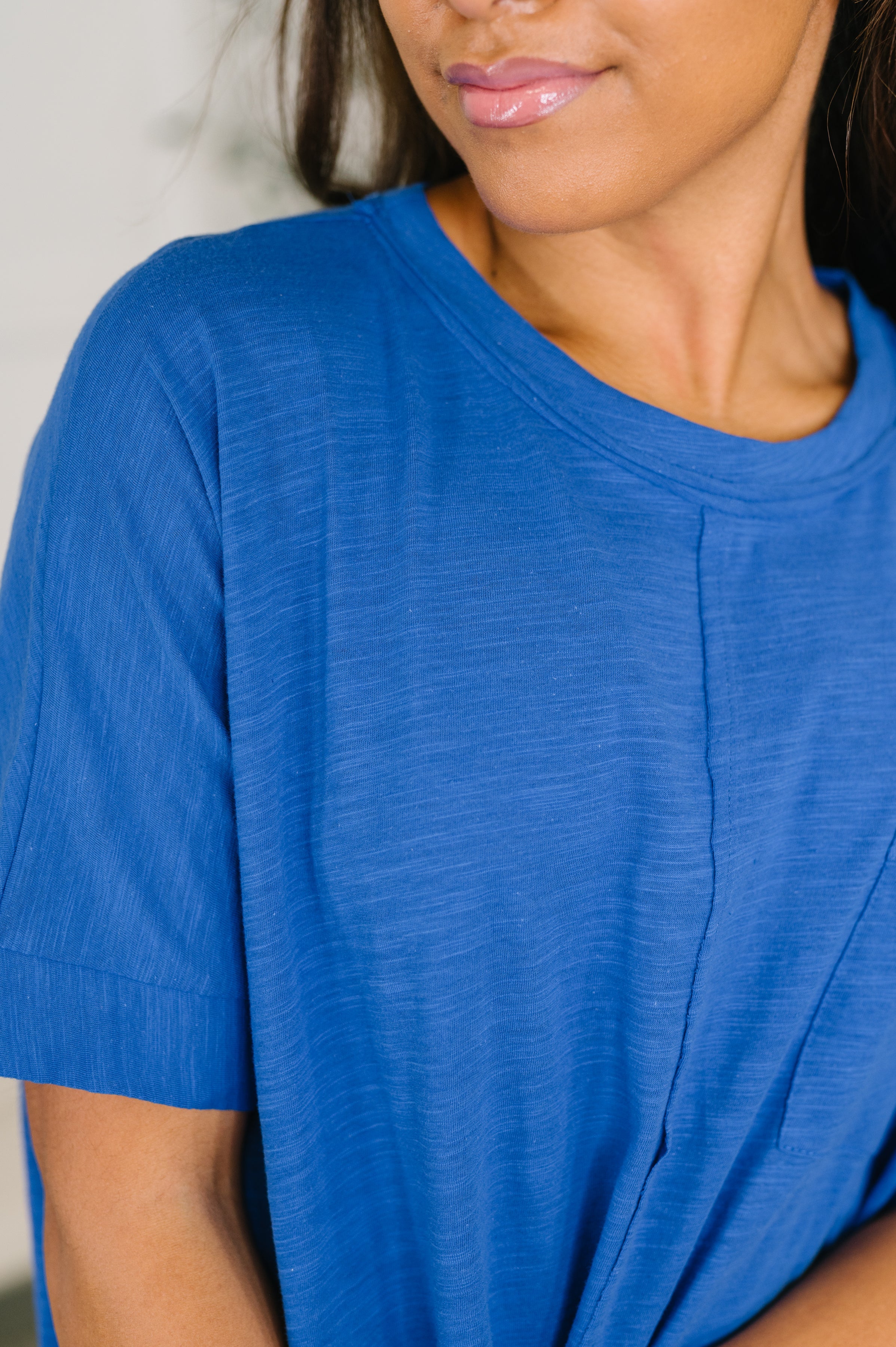 Close-up of soft blue relaxed knit tee with crew neckline and subtle seam detail on woman’s upper torso