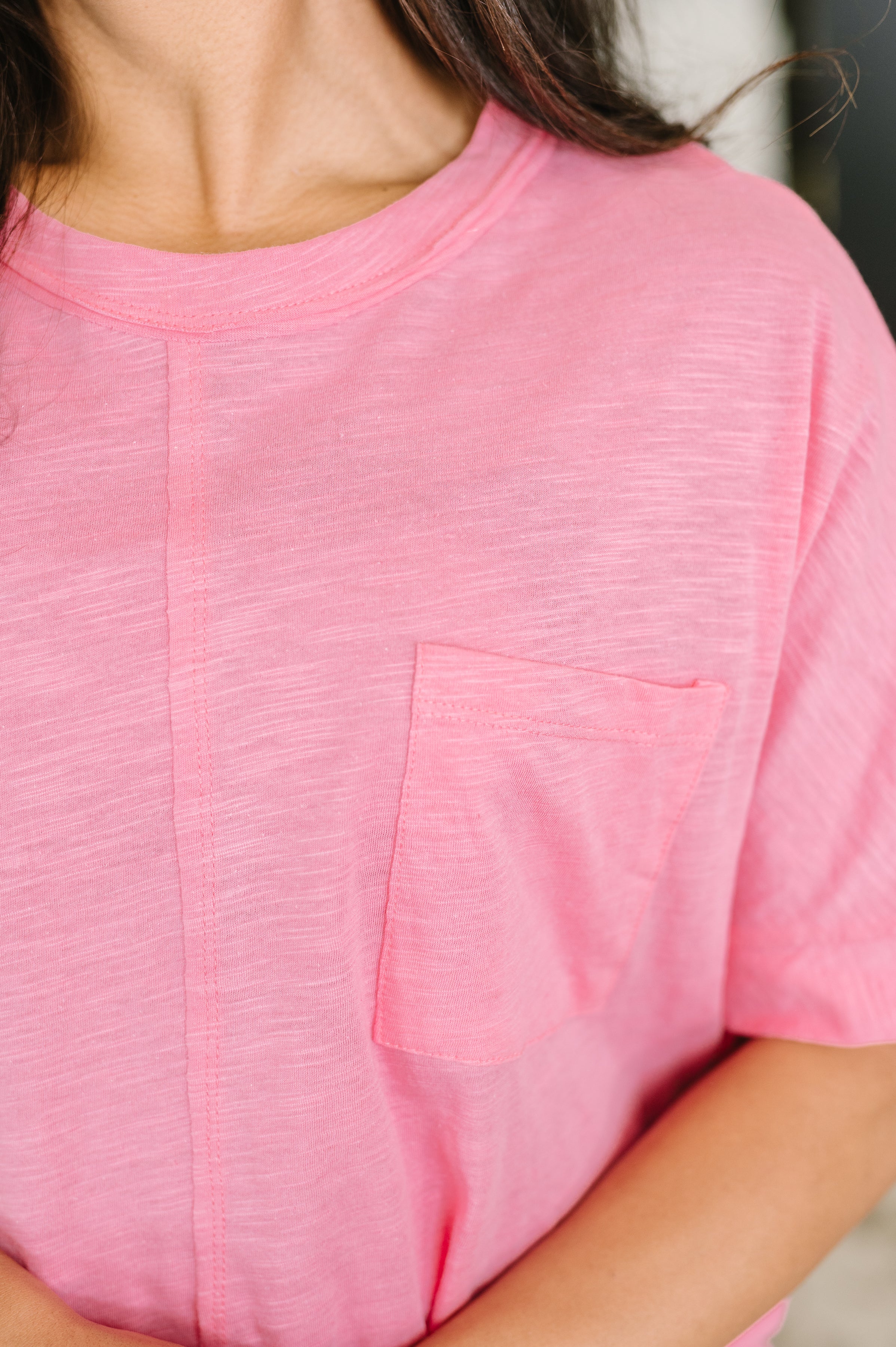 Close-up of soft pink relaxed knit tee with crew neck and small chest pocket on model's torso