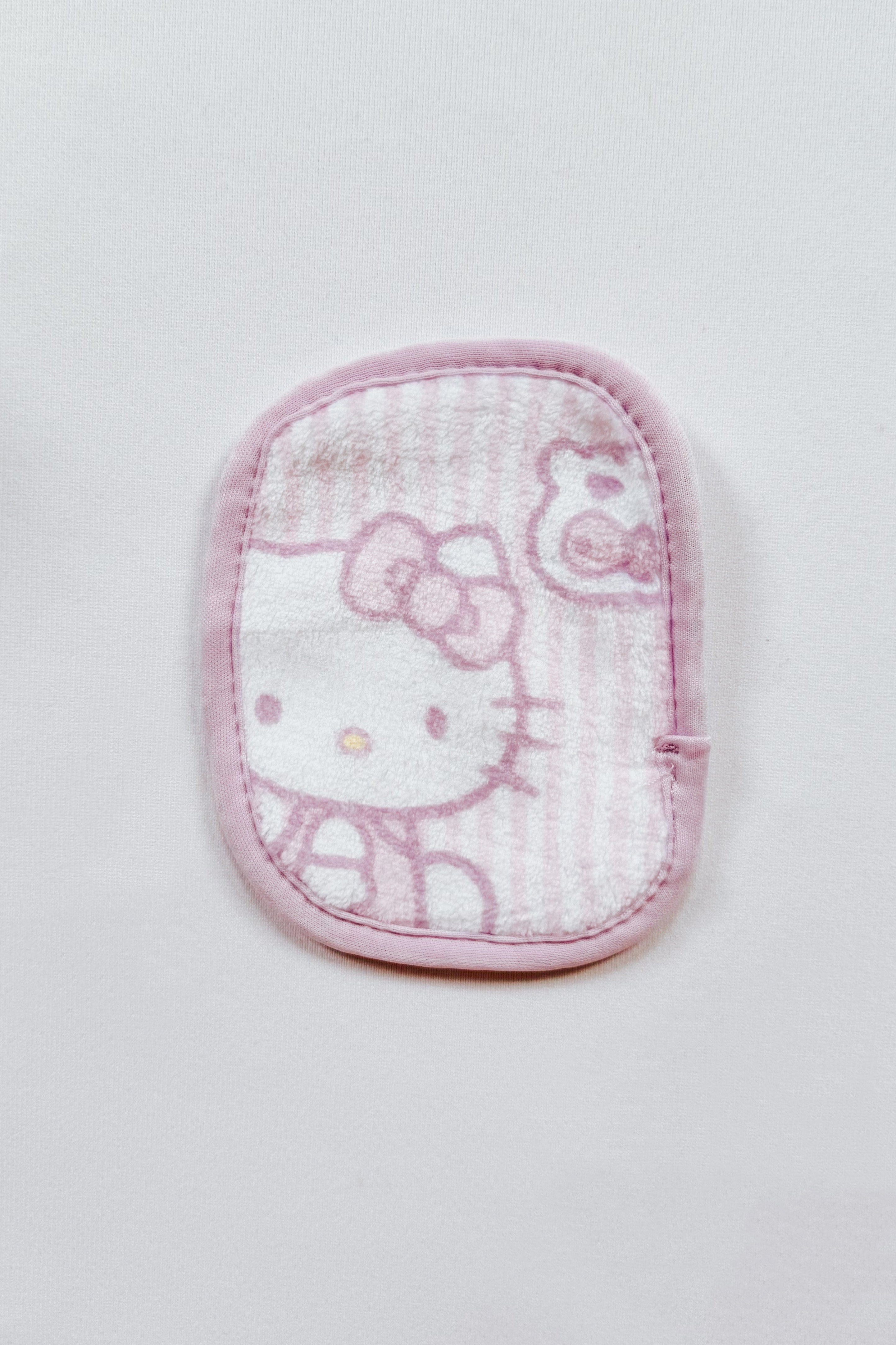 Pink and white soft makeup eraser cloth featuring Hello Kitty and bear design with rounded edges on white background