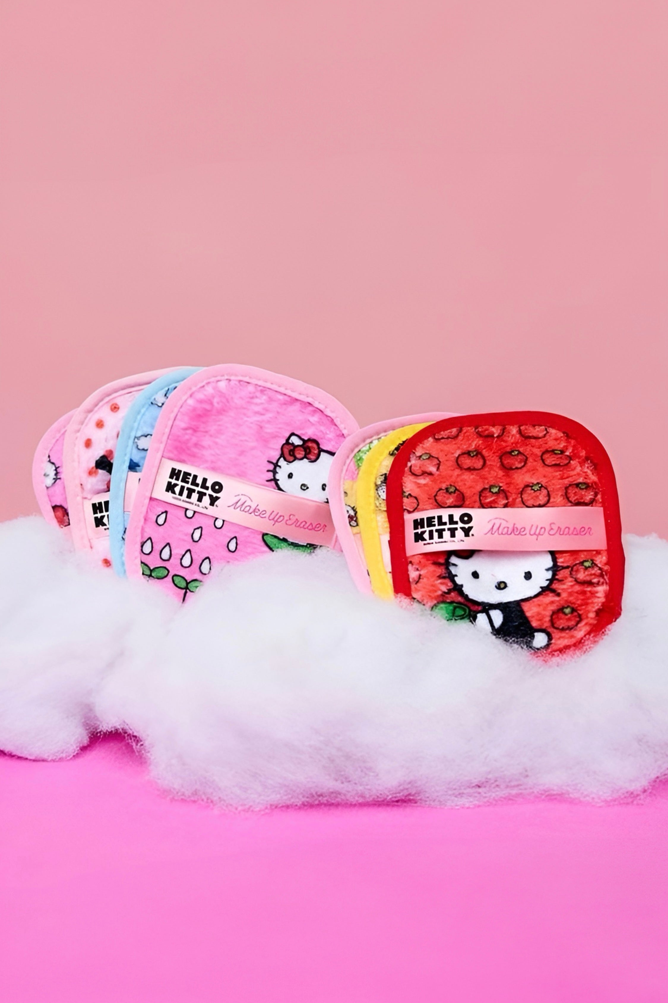 Colorful set of Hello Kitty makeup eraser pads in red, pink, yellow, and blue with playful fruit patterns on pink background