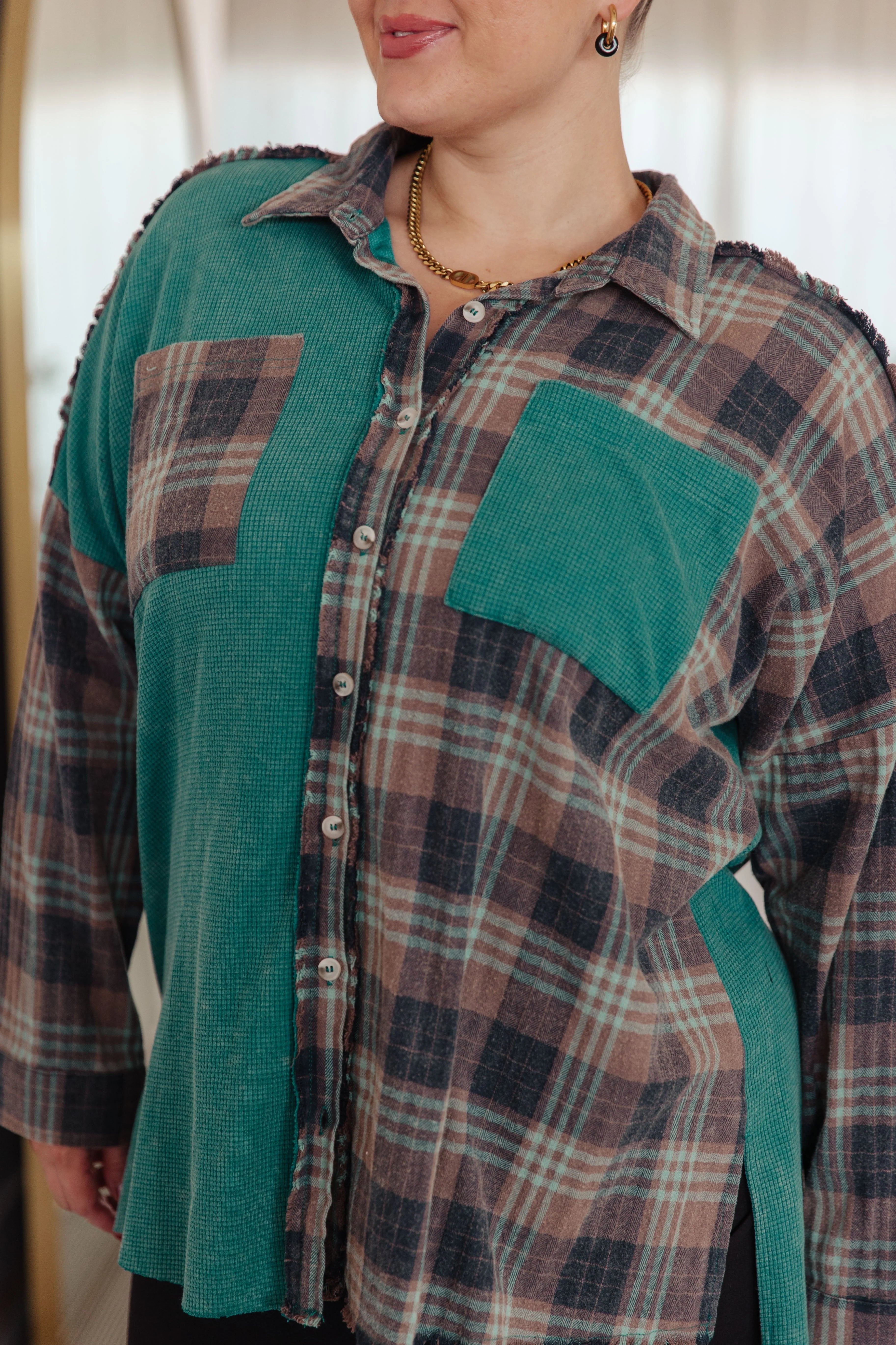Woman wearing a teal plaid thermal button-up with contrasting pockets and a relaxed fit, styled with gold earrings and necklace