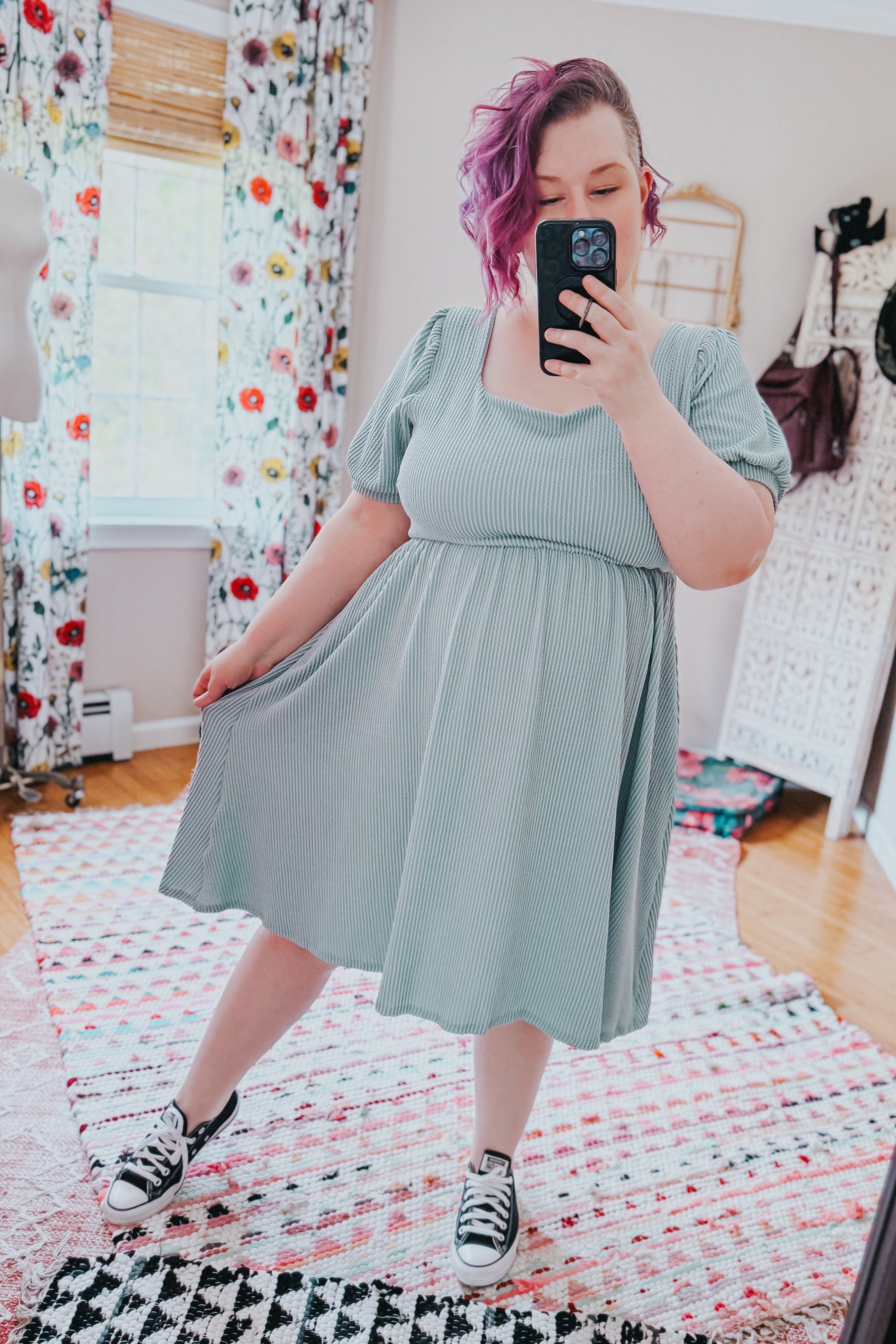 Woman with purple hair wearing a light sage ribbed knit dress with puff sleeves and black sneakers taking a mirror selfie