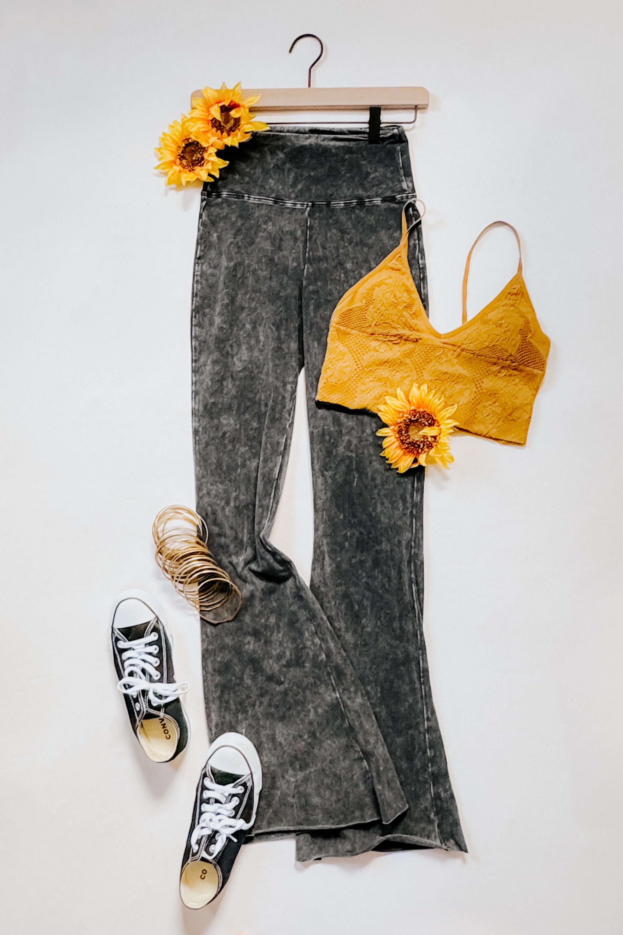 Ash black acid wash flared pants paired with a mustard textured crop top and casual sneakers styled with sunflowers