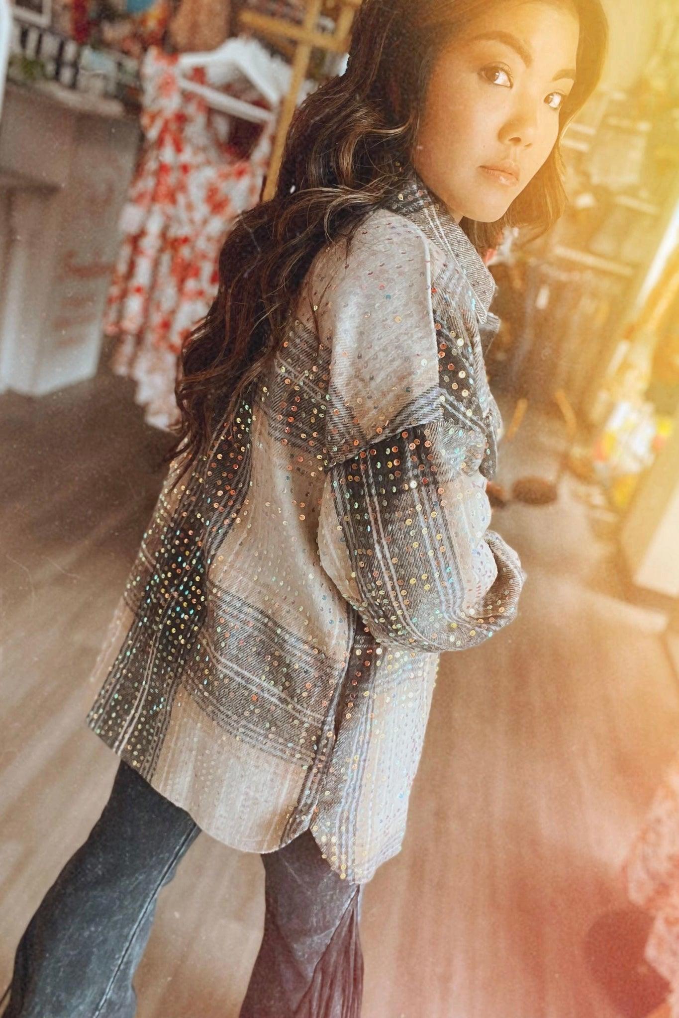 Woman wearing beige and black sequin plaid shacket in cozy boutique setting with warm sunlight filtering through windows