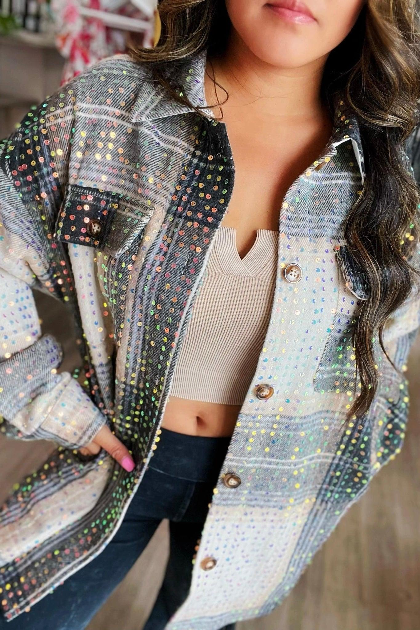 Woman wearing beige and black sequin plaid shacket over beige ribbed crop top with long dark hair styled in loose waves