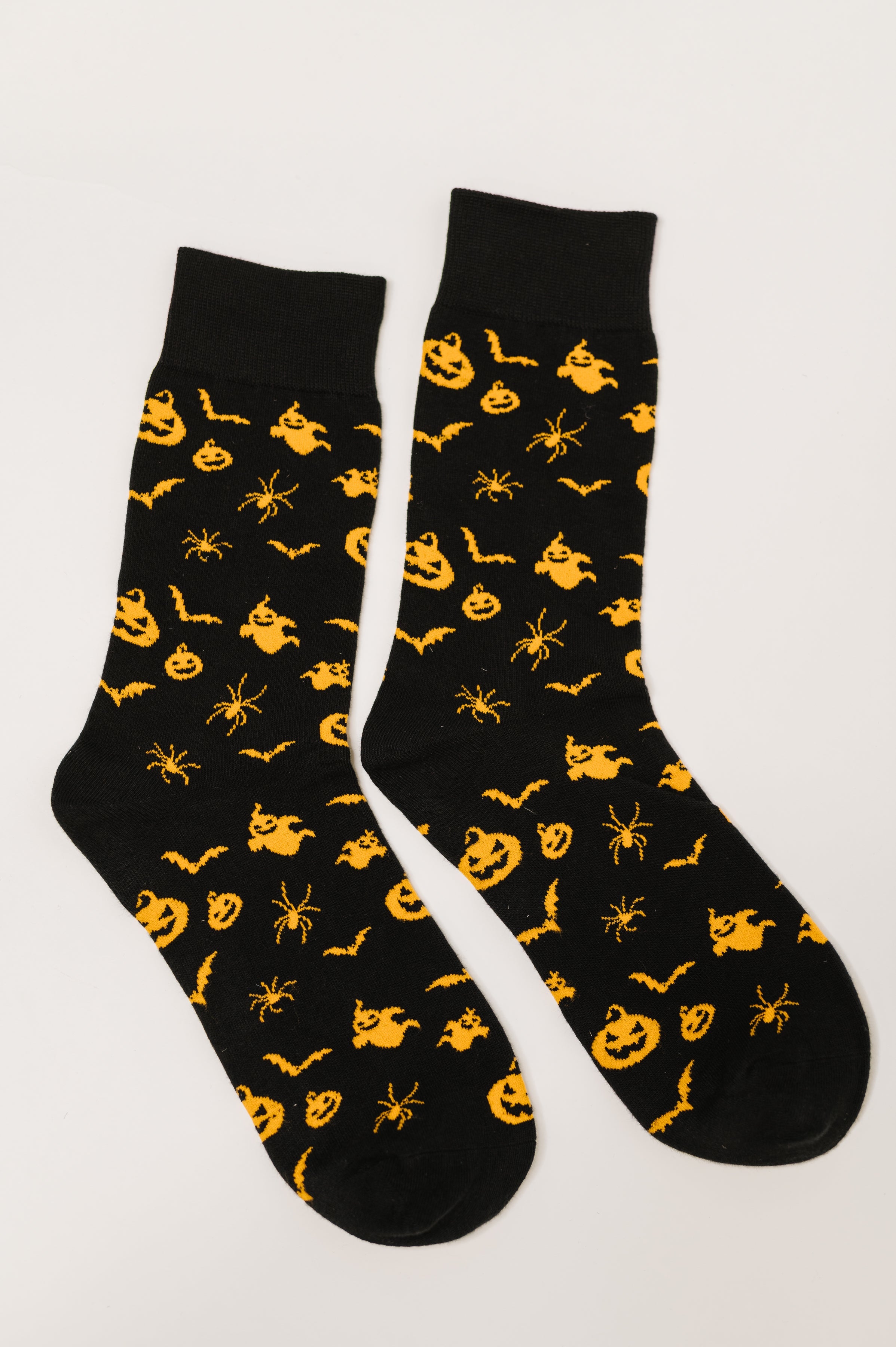 Pair of black quarter socks featuring orange Halloween-themed pumpkin, ghost, spider, and bat patterns