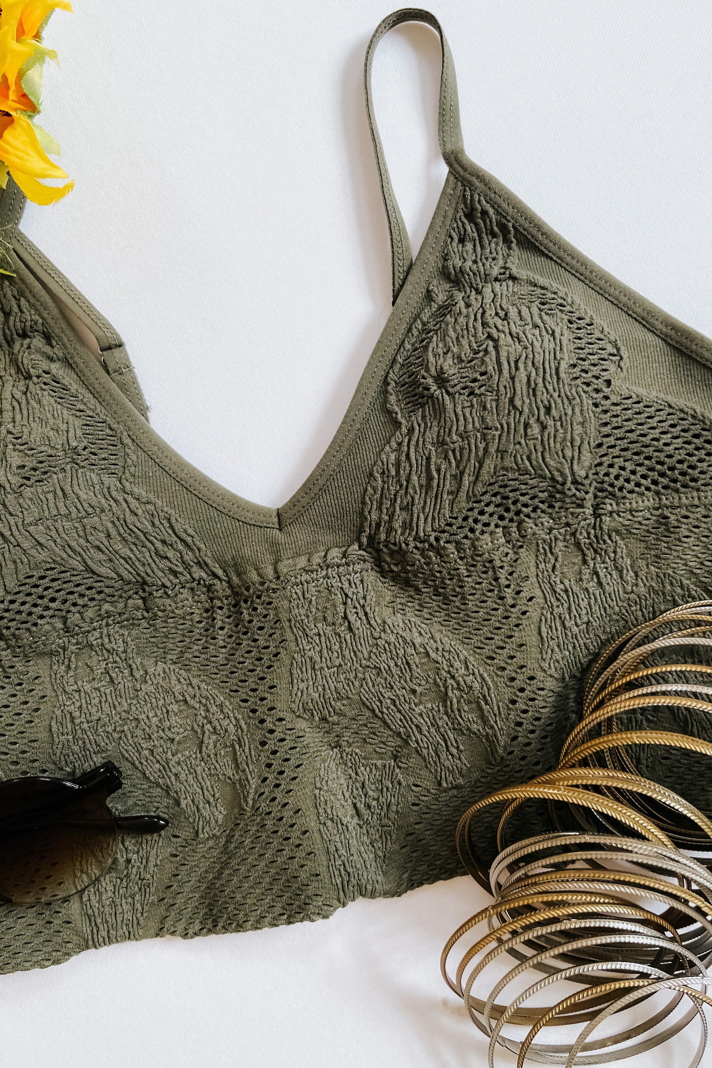 Olive textured seamless brami with thin straps, styled flat with sunglasses and stacked metallic bangles