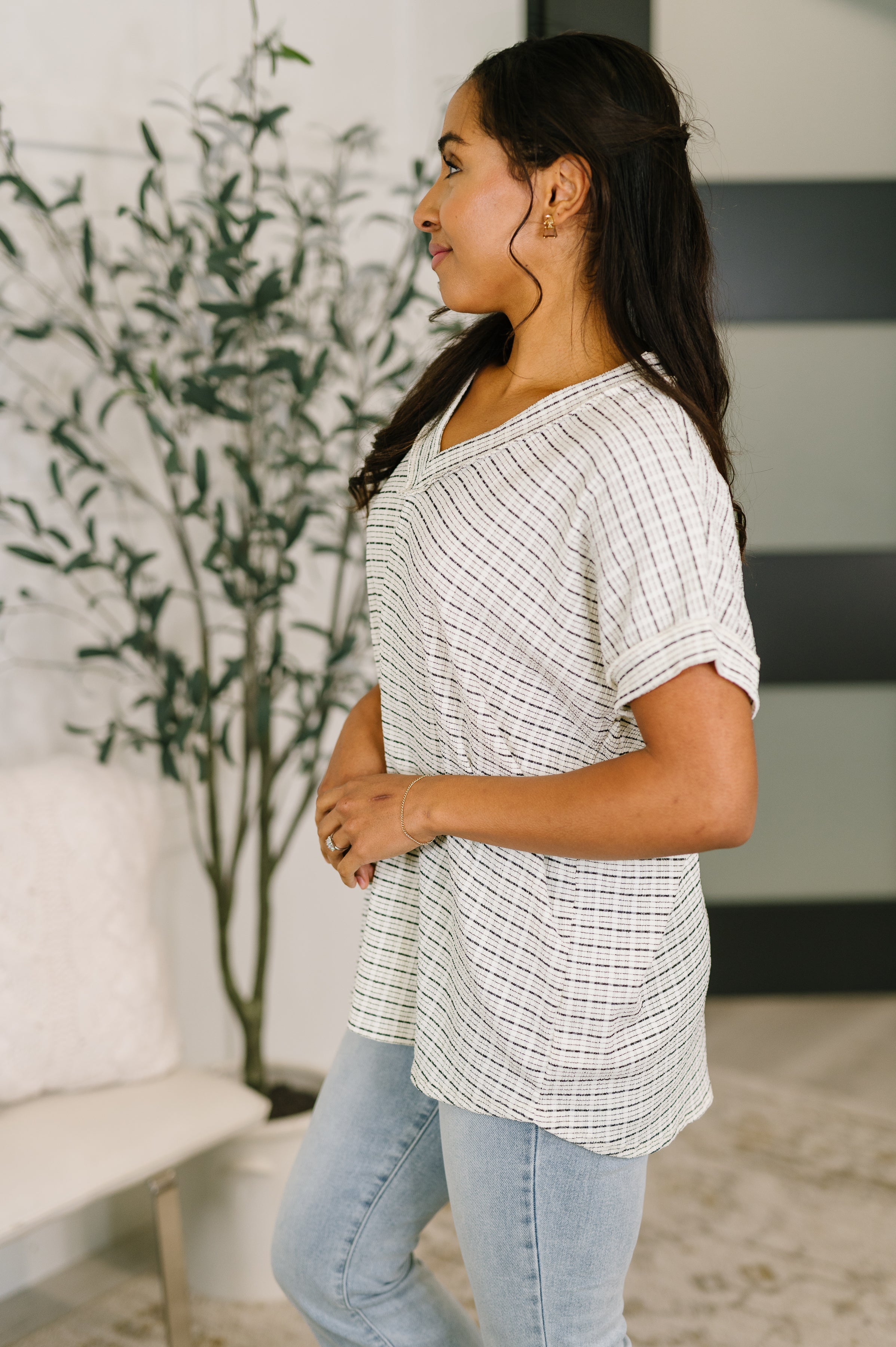 Side profile of cream textured knit V-neck top with short sleeves in a casual, eclectic, size-inclusive style setting