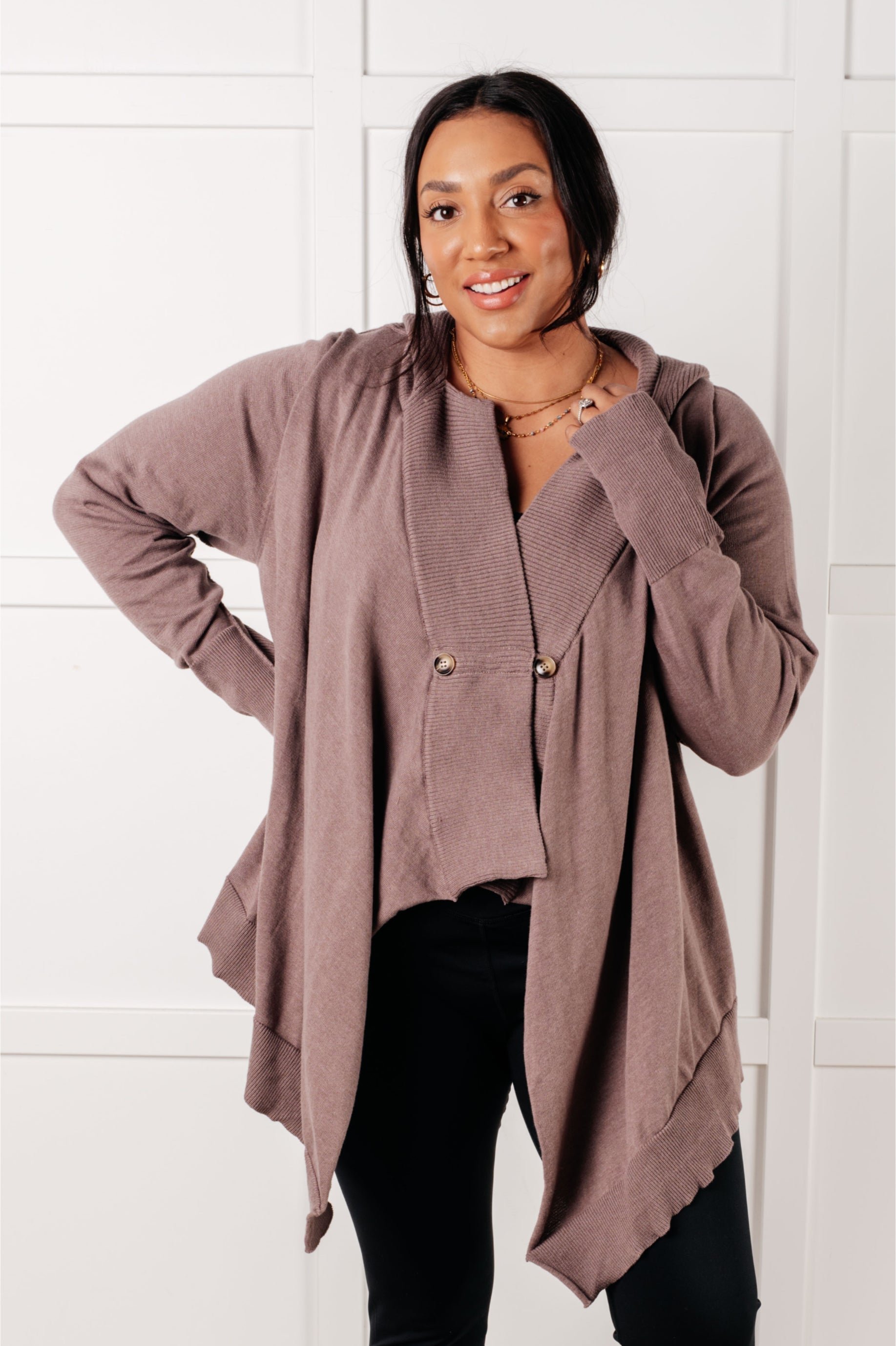 Woman wearing a mocha cardigan with button details and relaxed fit posing with hand on hip indoors