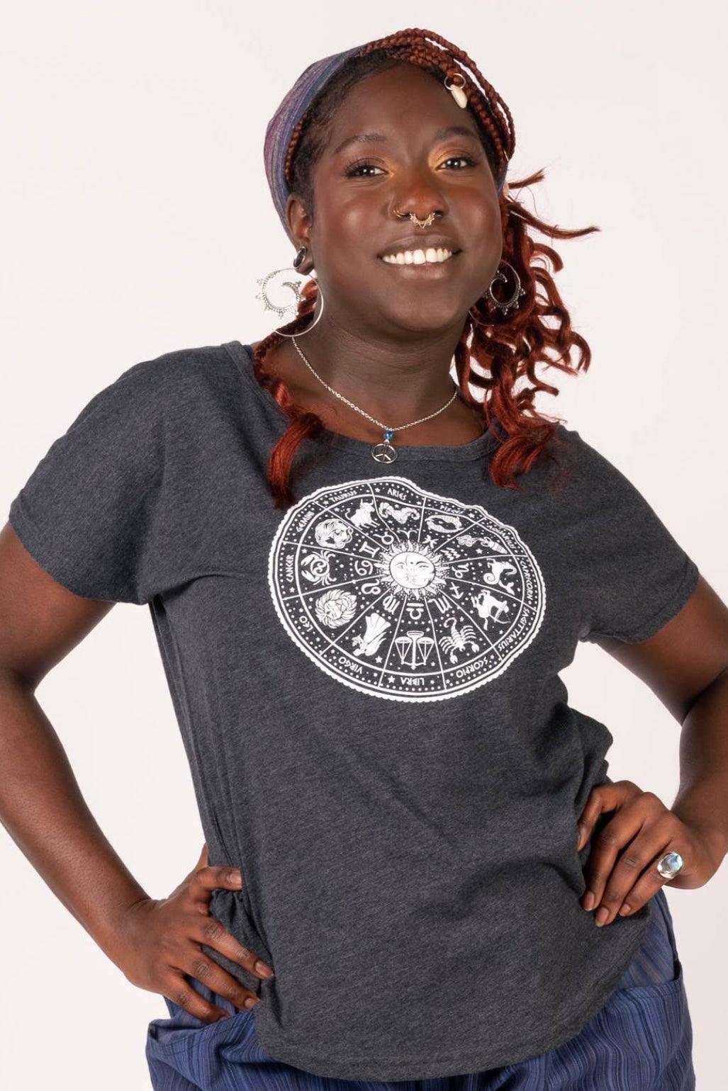 Woman wearing charcoal slouchy top with white zodiac wheel design smiling confidently against light background