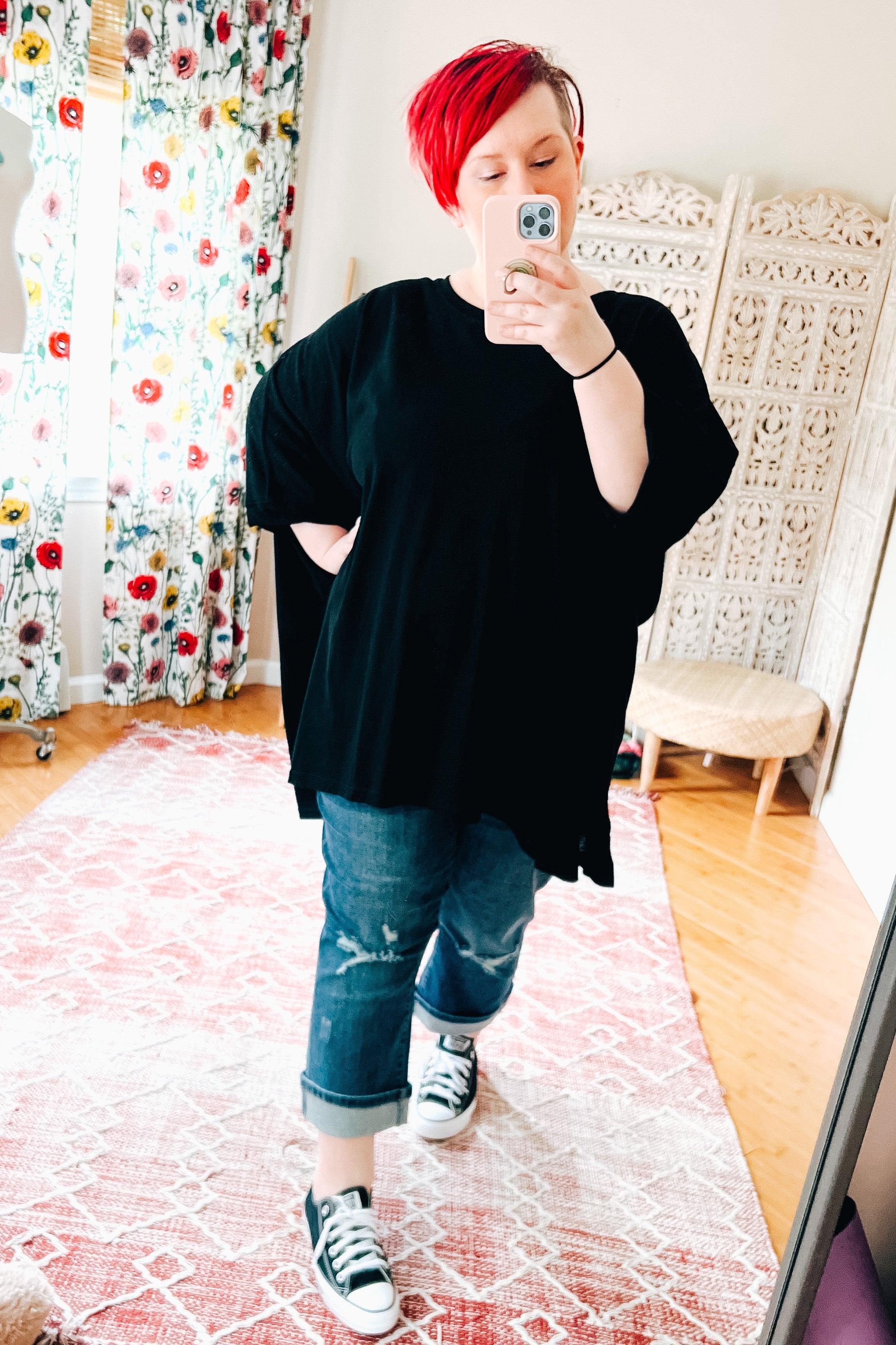 Woman with bright red hair wearing oversized black All My Life Boxy Top and cuffed jeans taking mirror selfie indoors