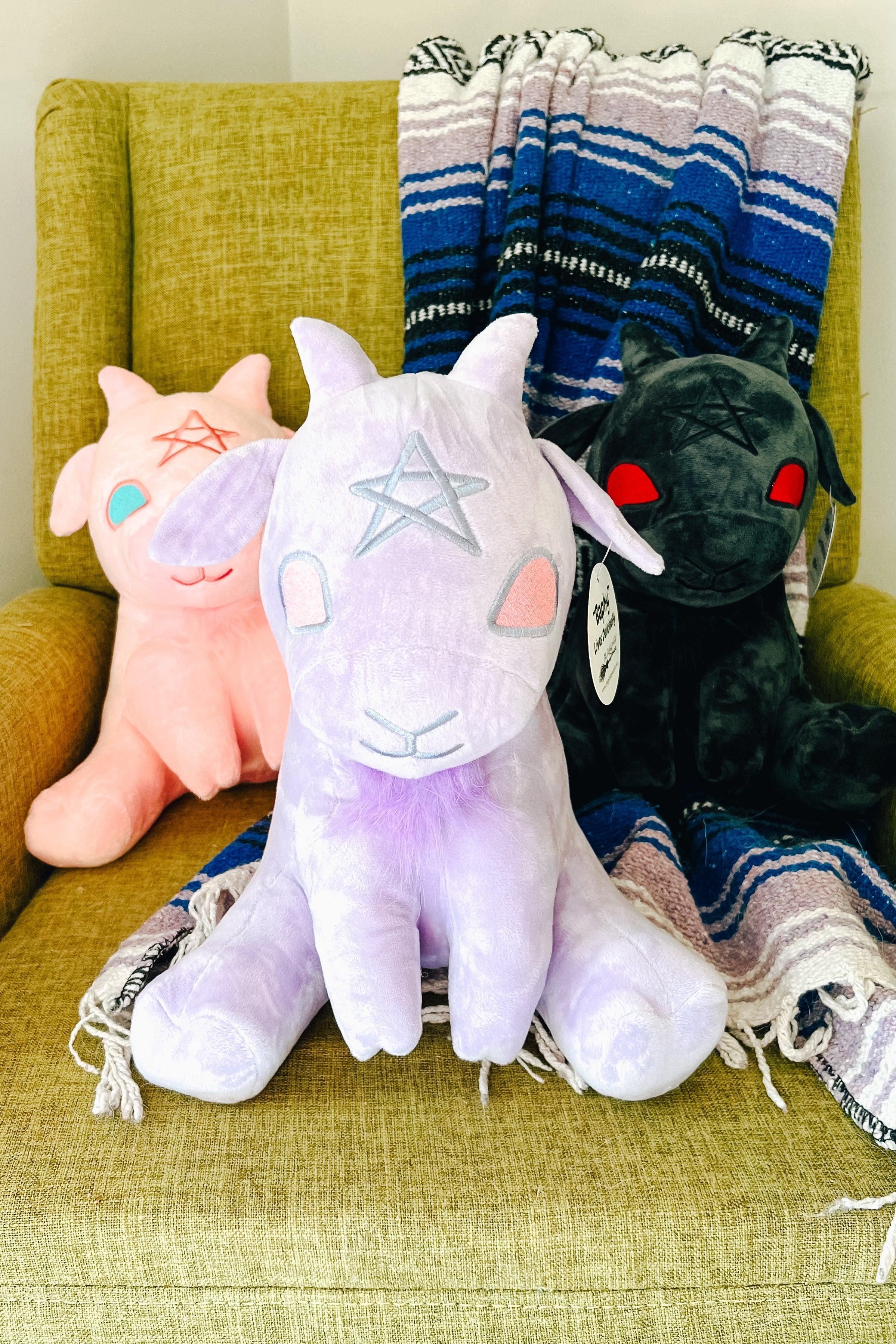 Lavender Baphy Witchy Baby Goat plush with silver star on forehead seated on green chair with blue striped blanket behind