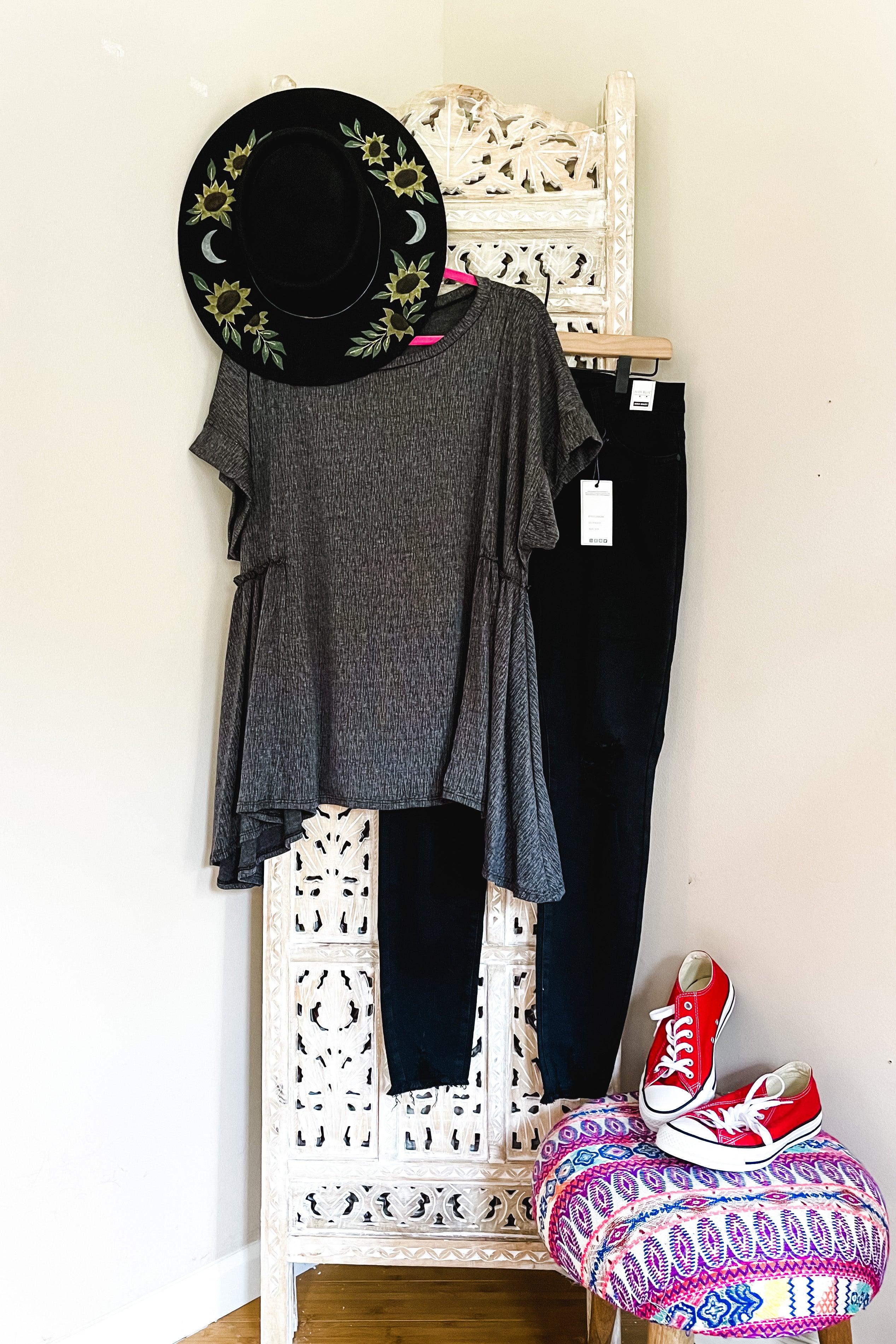 Dark gray oversized tunic with asymmetrical hem paired with black pants and black hat with sunflower embroidery