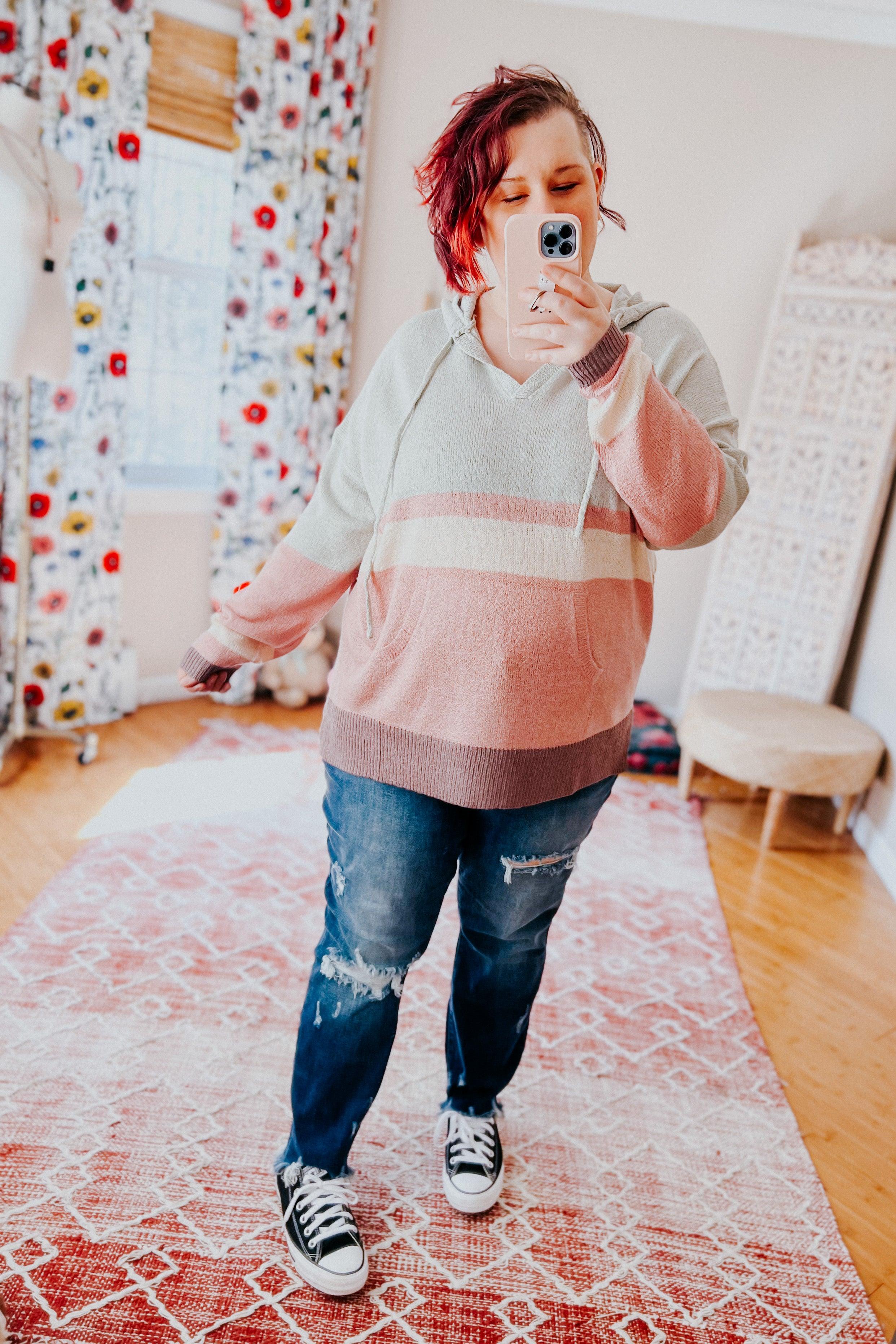 Woman wearing Boy Problem Spring Hoodie in pastel hues with ripped jeans and black sneakers taking a selfie indoors