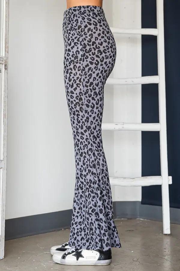 Side view of woman wearing blue leopard print fitted bell bottom pants and black and white star sneakers indoors