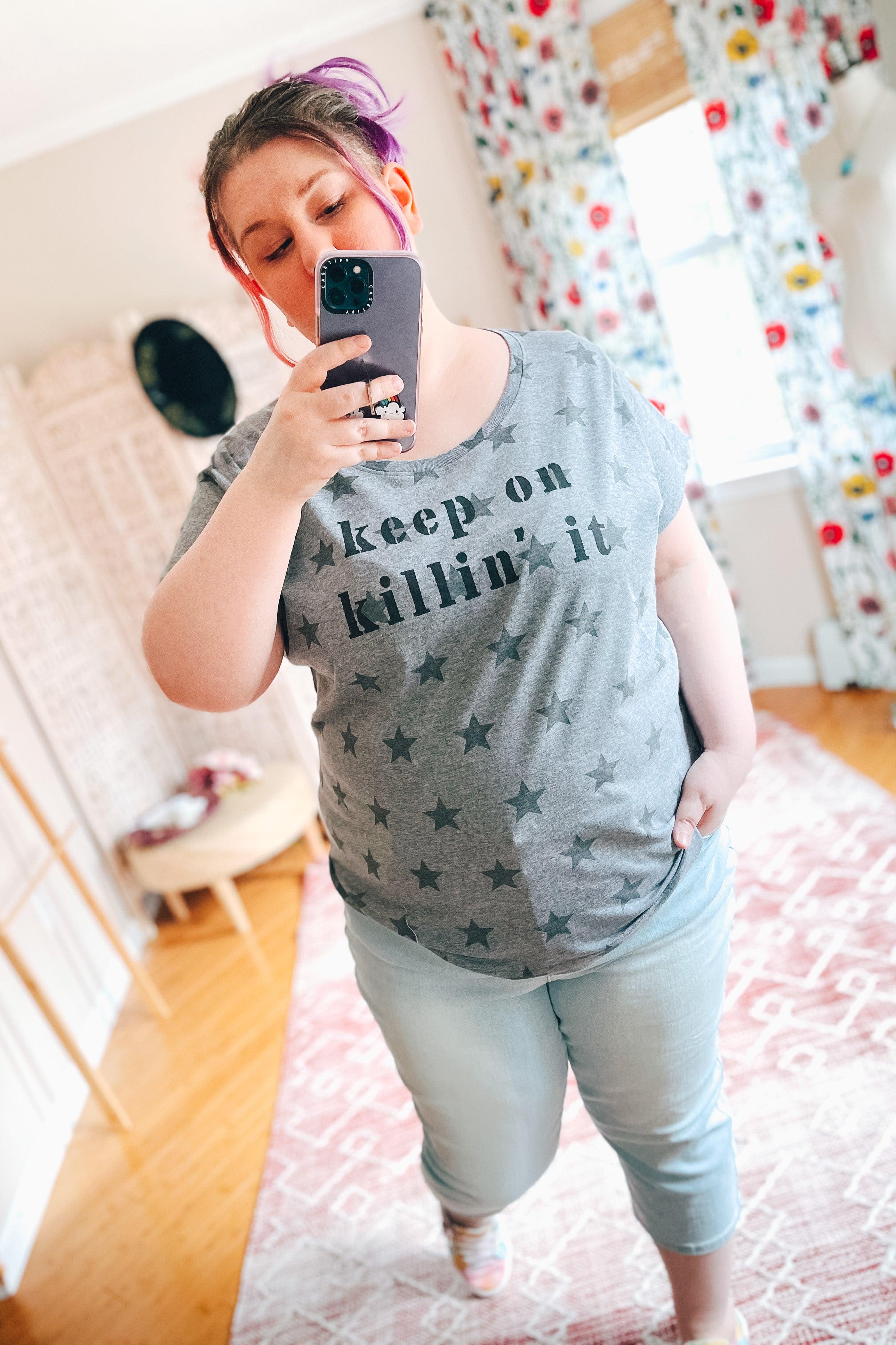 Woman taking indoor mirror selfie wearing grey Keep On Killin’ It Star Tee with scattered star pattern and light wash jeans