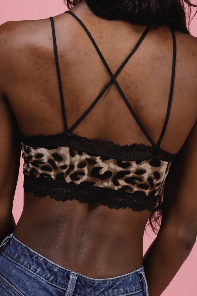 Close-up of a brown and black animal print bralette with thin crossed straps on a model’s back against pink background