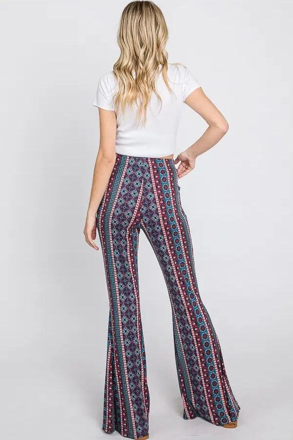 Woman wearing blue patterned flare pants with vertical stripes and a white fitted short sleeve top viewed from behind