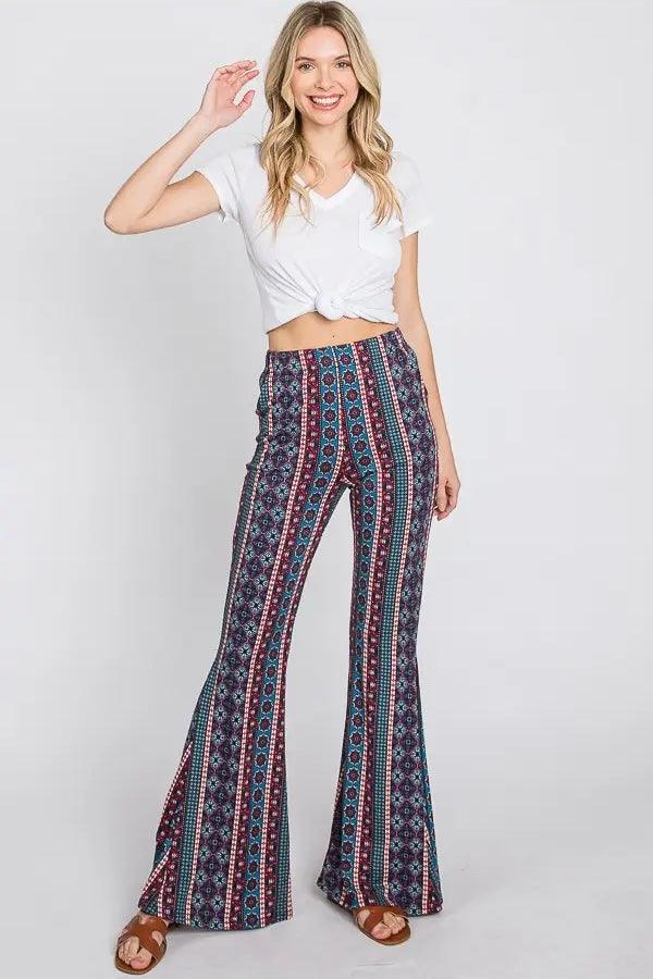 Woman wearing blue patterned wide-leg pants with vertical stripes paired with a knotted white short sleeve top