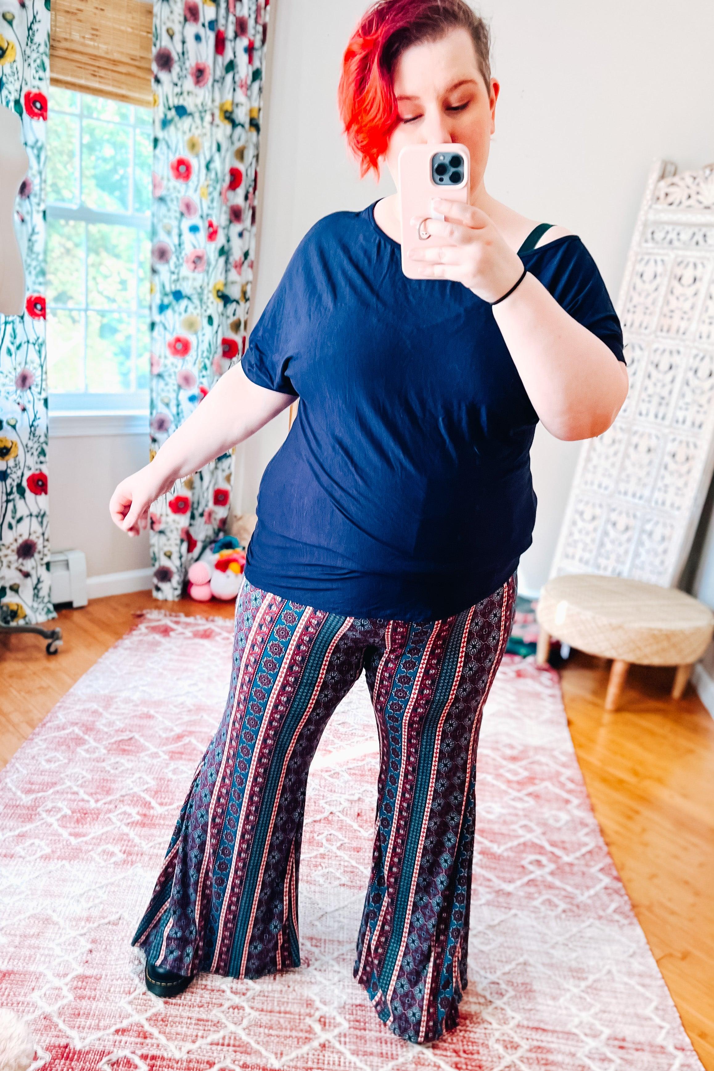 Woman wearing blue patterned boho wide-leg pants with vertical stripes paired with a loose navy blue top indoors
