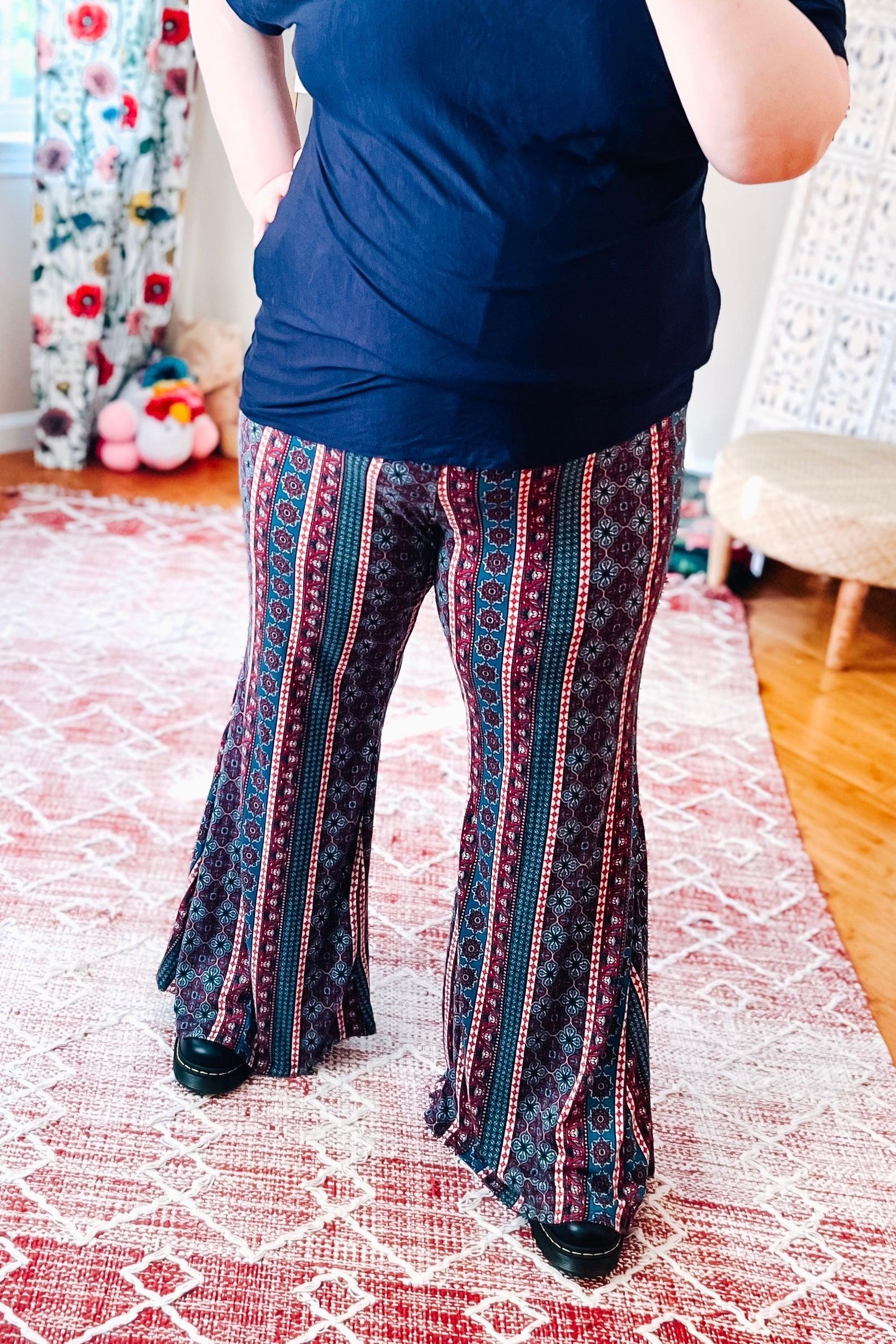 Woman wearing flared pants with vertical geometric stripes in blue, red, and white paired with a black top indoors