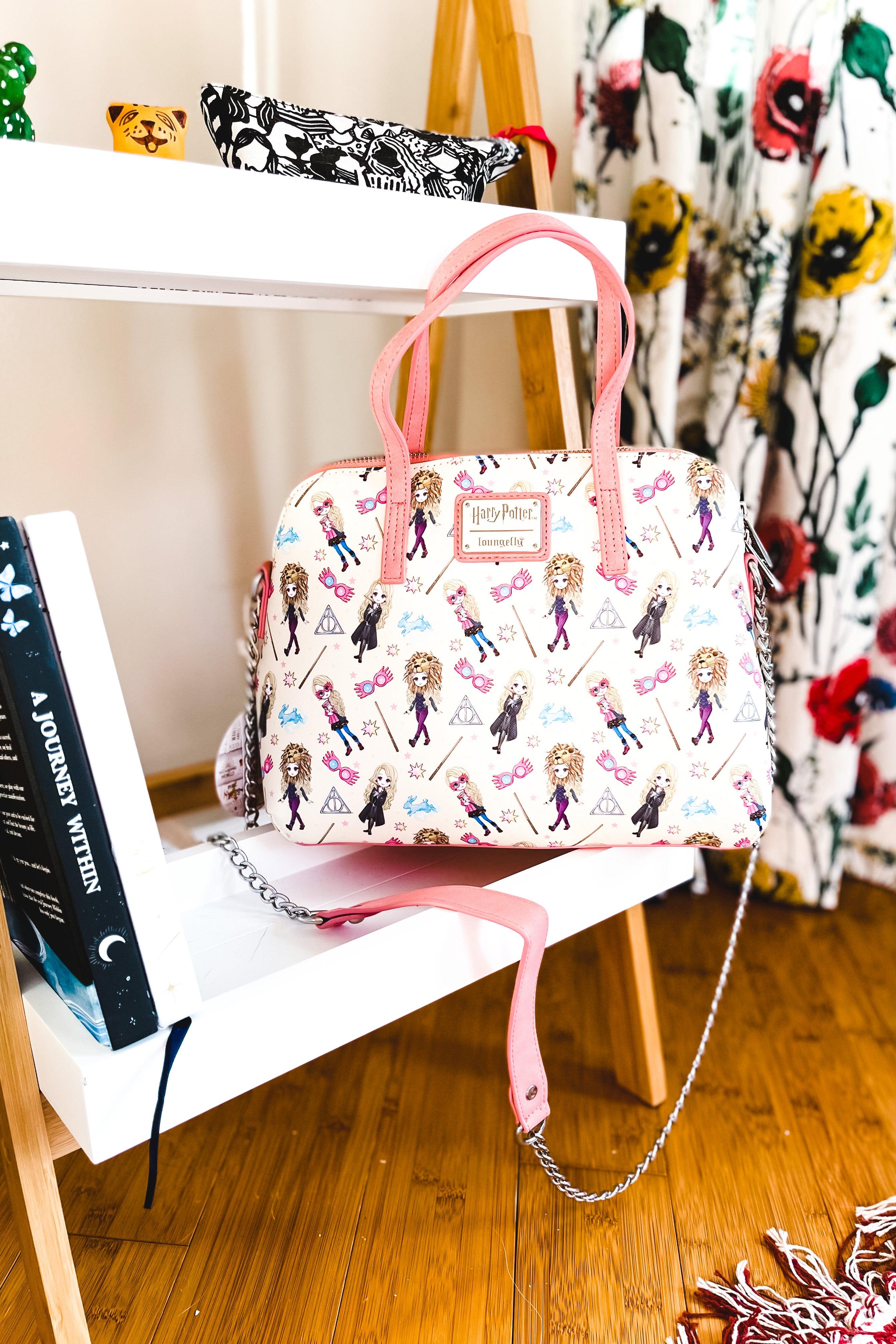 Cream-colored loungefly handbag with pink handles and a whimsical pattern of illustrated Harry Potter characters and magical symbols