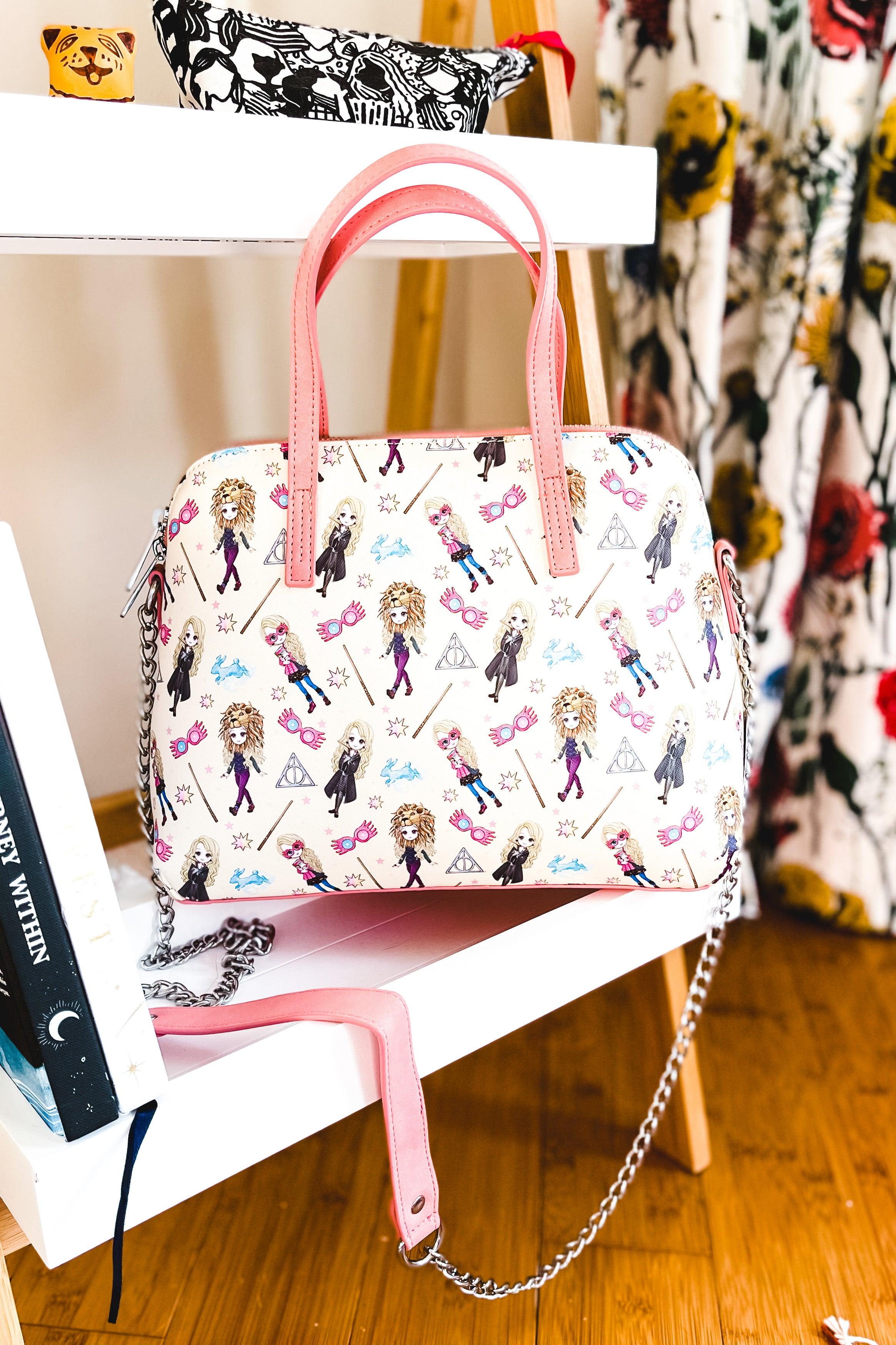 Cream loungefly handbag with pink handles and playful Harry Potter characters holding wands and glasses on a light background