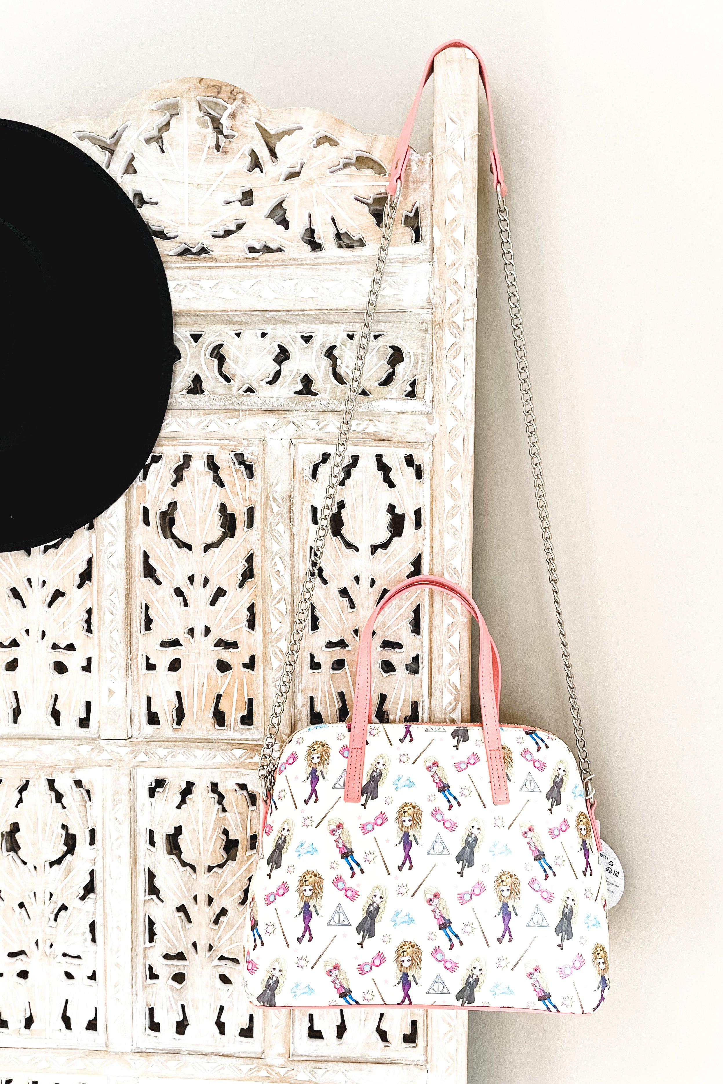 Cream loungefly handbag with pink handles and chain strap decorated with playful Harry Potter characters and magical symbols pattern