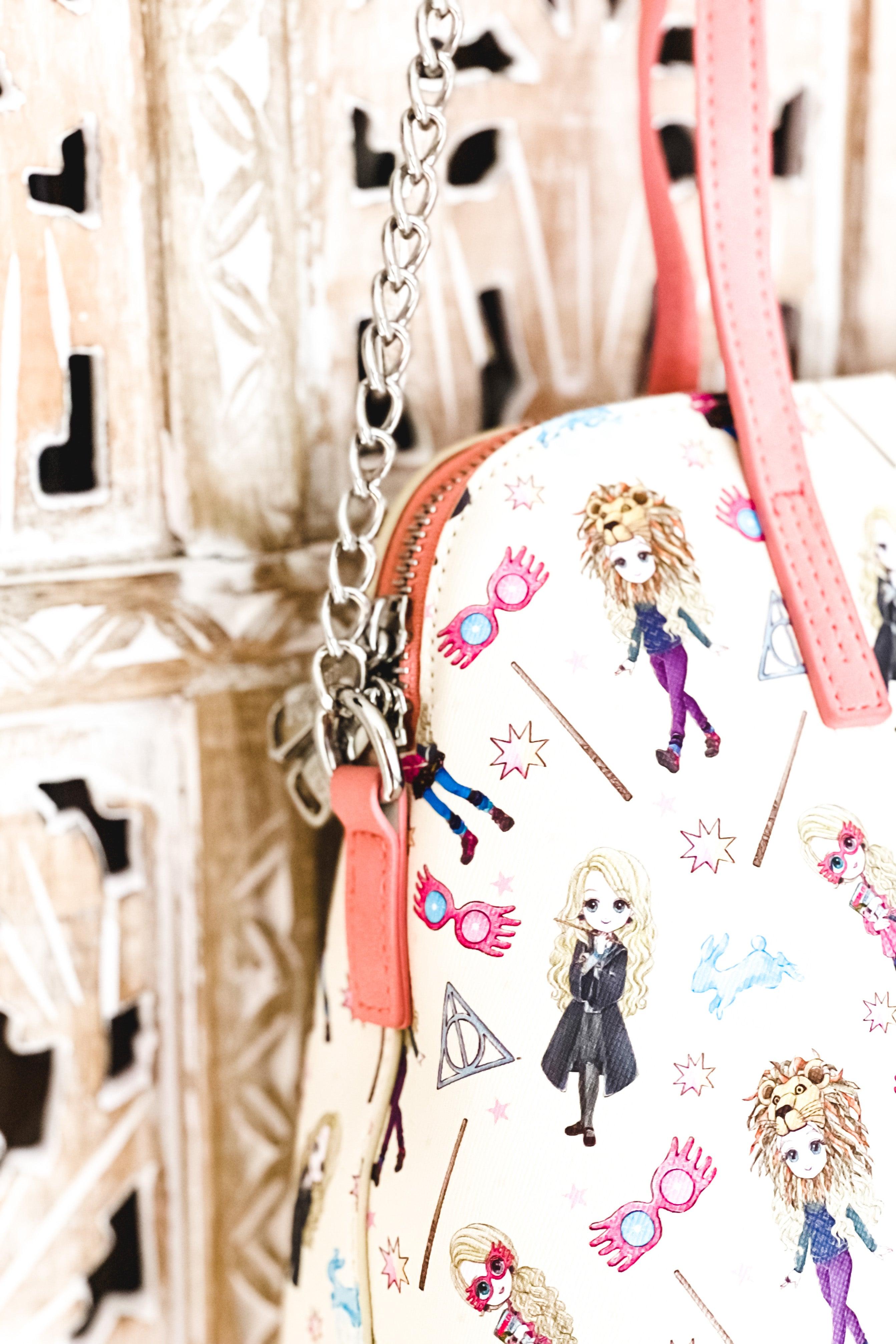 Cream loungefly handbag with coral handles and chain strap featuring illustrated Harry Potter characters, magical wands, and whimsical symbols pattern