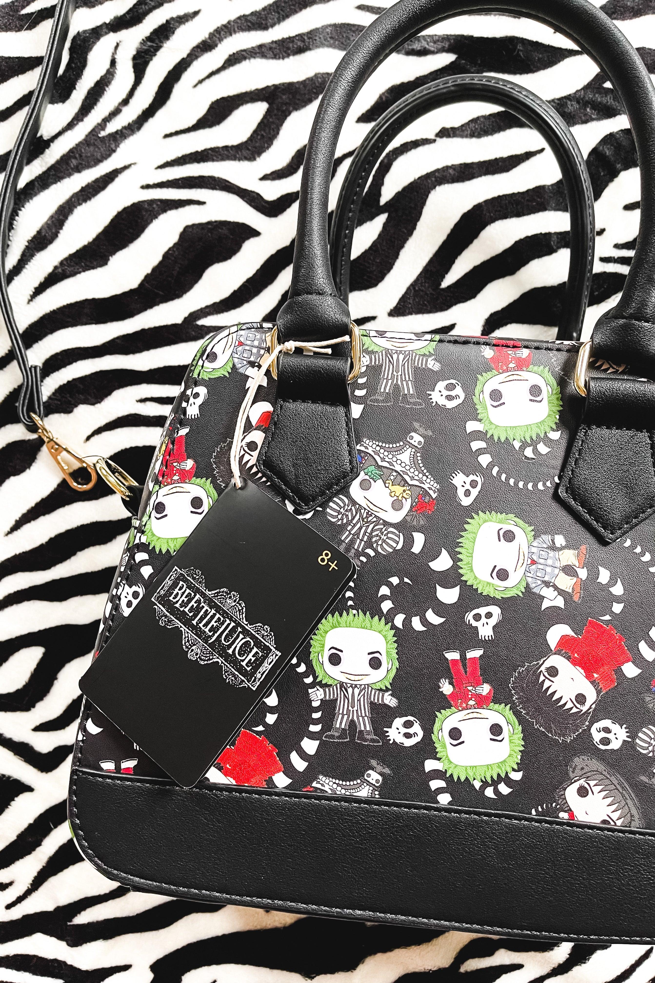 Black loungefly handbag with cartoon Beetlejuice characters and skull accents on black background with black handles and trim