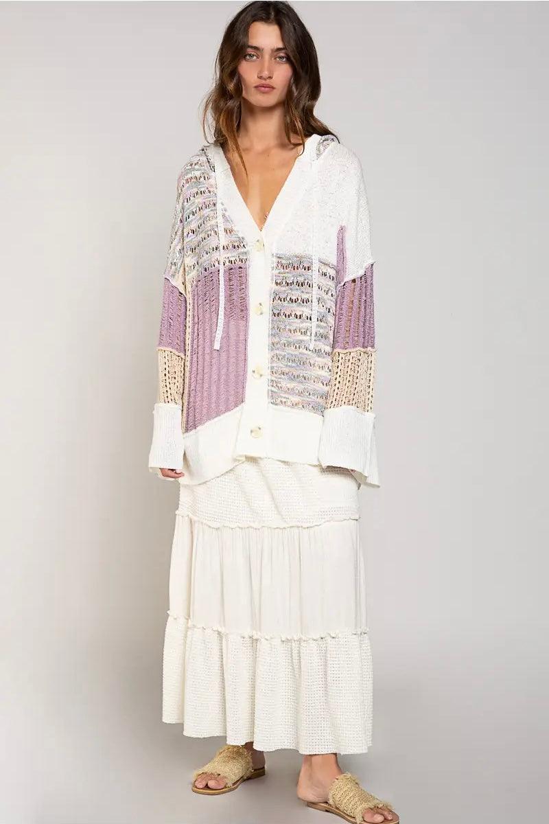 Relaxed lavender and cream open-knit cardigan with hood, button front, and textured patchwork details, styled with a tiered skirt