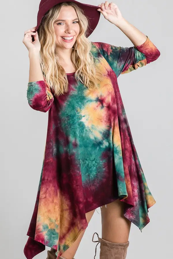 Flowy tie-dye dress in ruby, green, and mustard with an asymmetrical hem, styled with a wide-brim hat