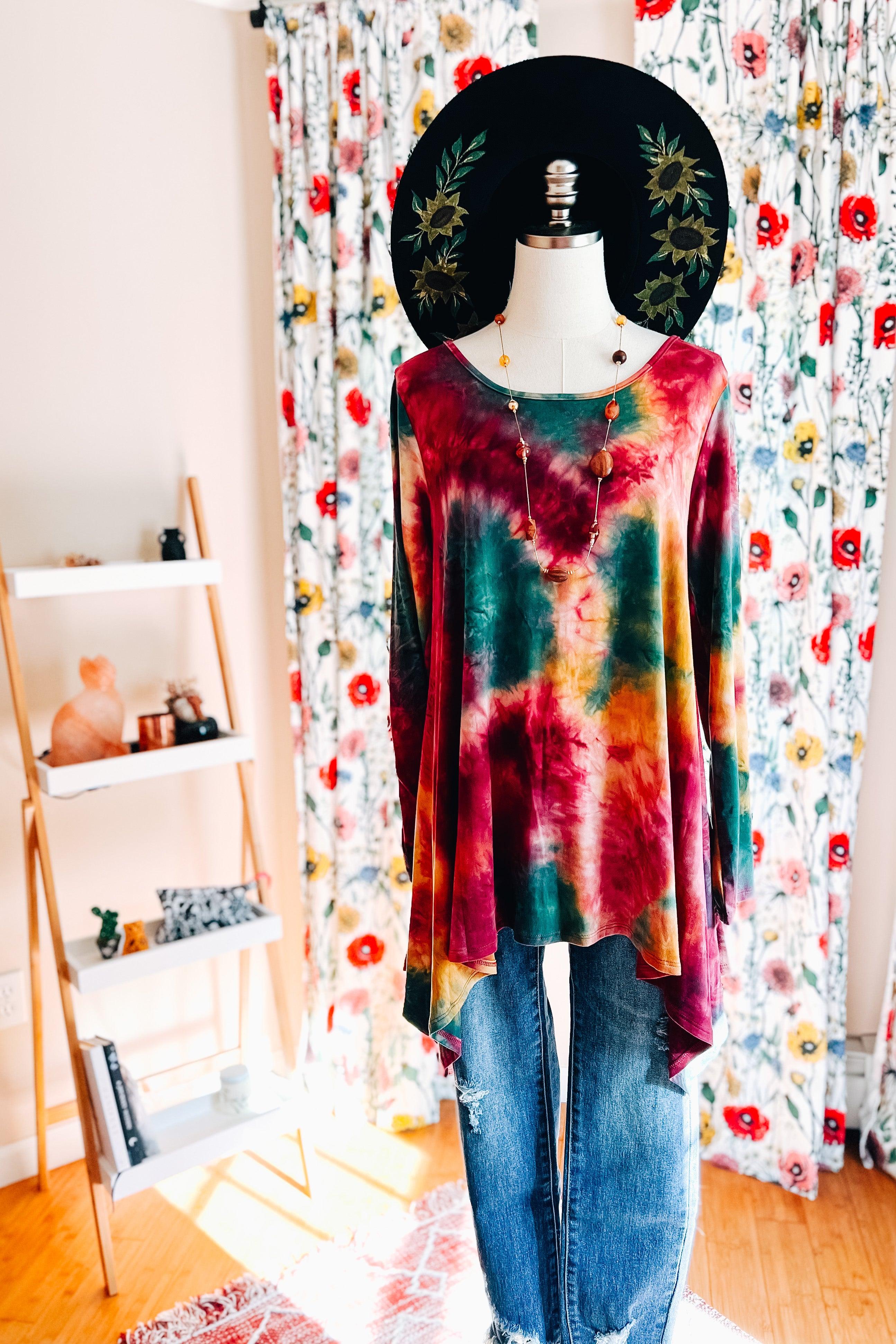 Loose-fitting long-sleeve tunic in ruby tie-dye with green and mustard highlights paired with distressed jeans and layered necklace