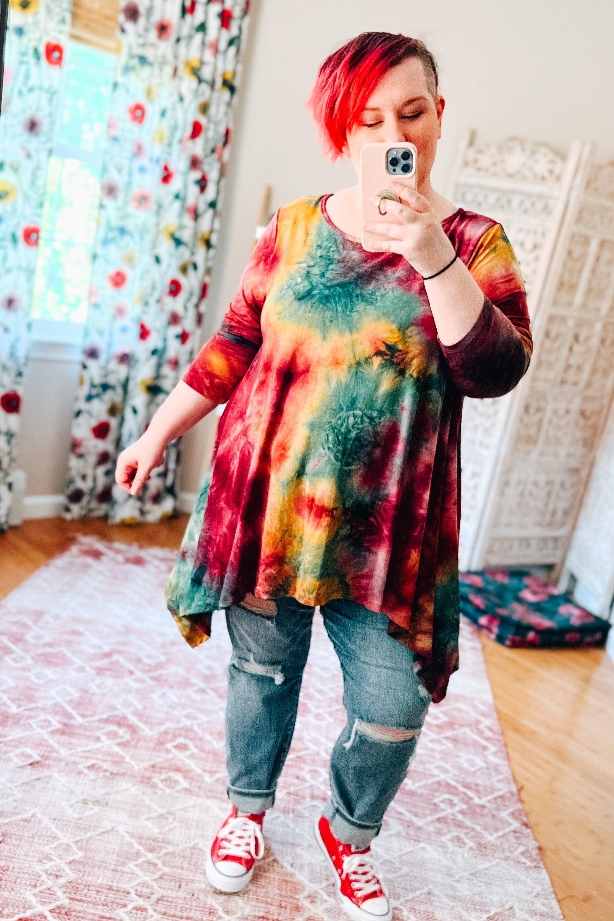 Flowy long-sleeve tunic in ruby tie-dye with green and yellow highlights, paired with ripped jeans and red sneakers
