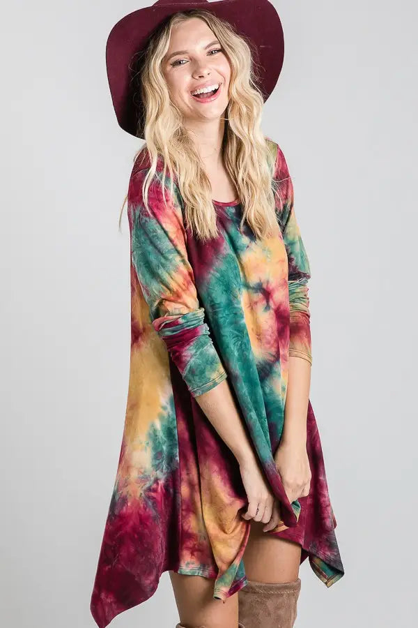 Long-sleeve tie-dye dress in ruby, green, and mustard hues paired with a wide-brimmed hat and knee-high boots