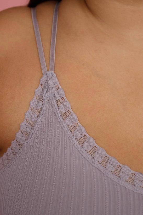 Close-up of lilac lace bralette featuring ribbed fabric and scalloped trim with double thin shoulder straps on model's skin