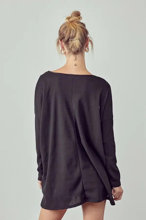 Back view of a person wearing a loose black oversized thermal tunic with a subtle center seam detail