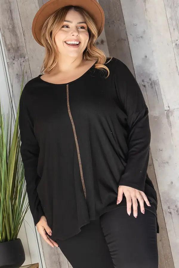Plus-size woman wearing a relaxed black thermal tunic with a decorative vertical seam and long sleeves indoors