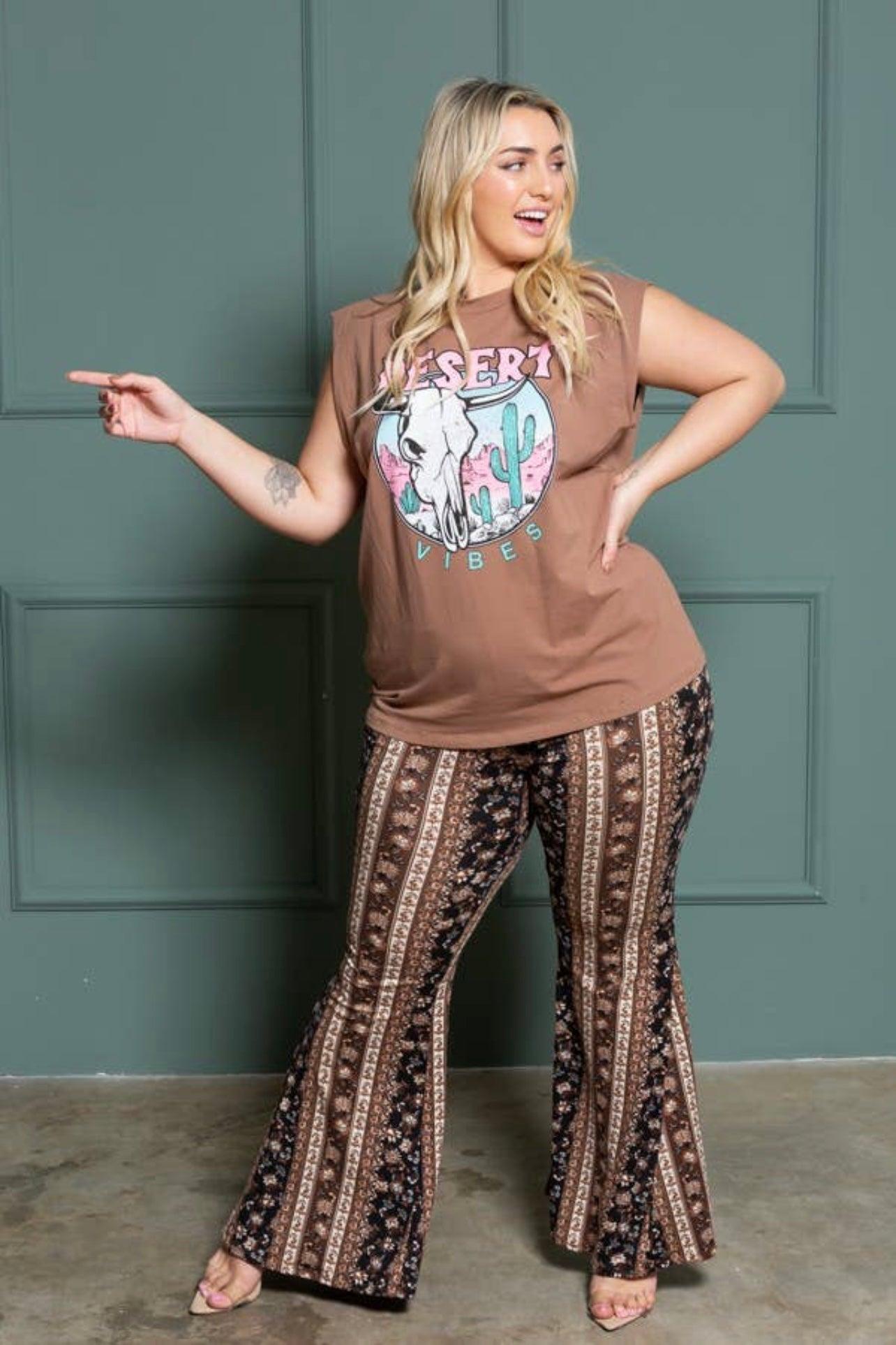 Curvy woman wearing earthy graphic sleeveless top and navy brown patterned bell bottoms with vertical paisley stripes indoors