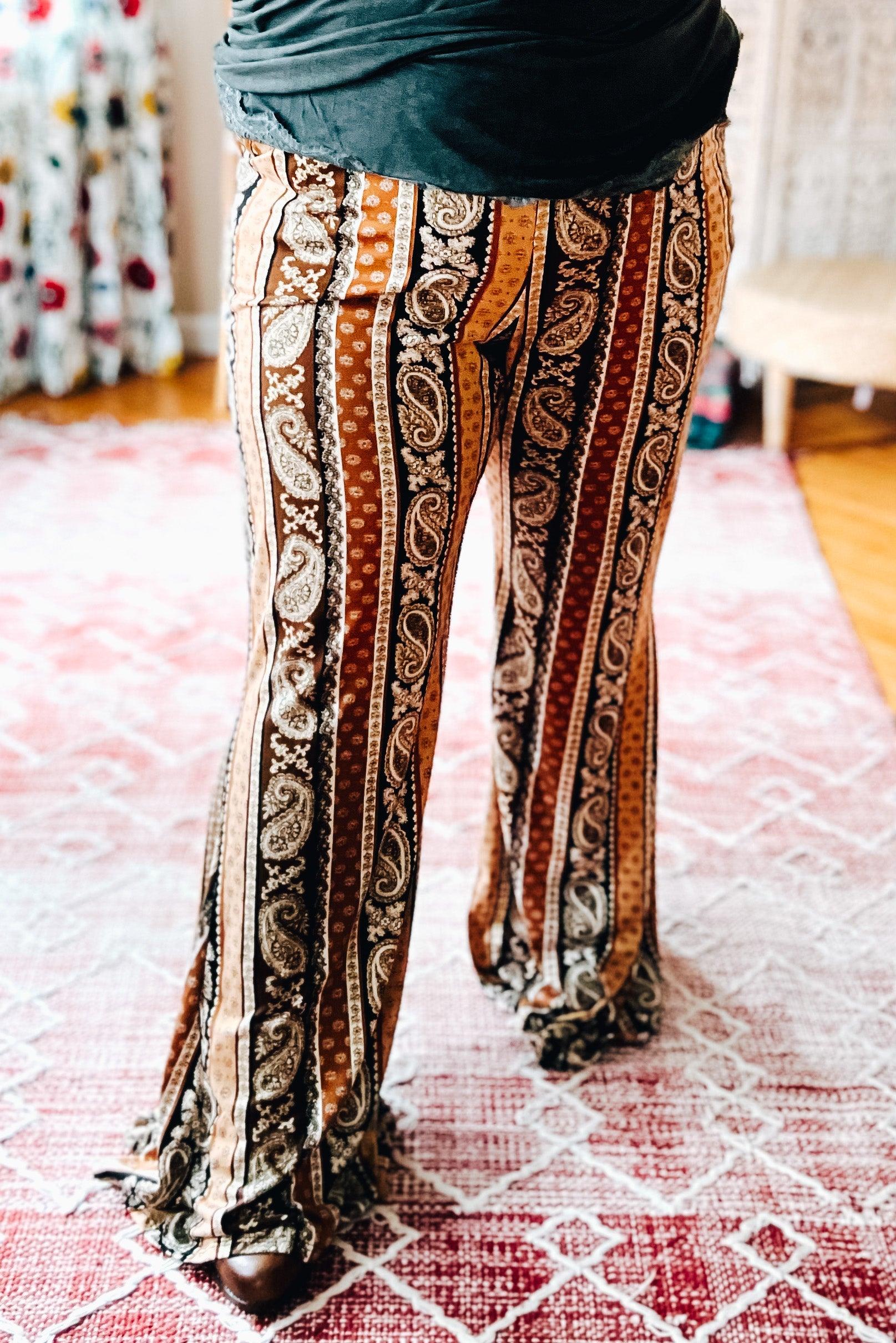 Rust-toned paisley and striped flared pants styled in a bold, eclectic home setting with a free-spirited vibe