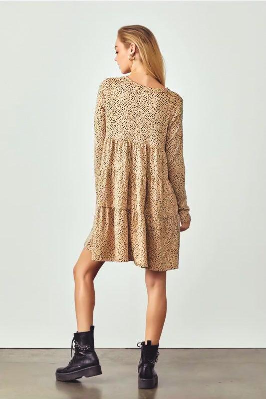 Woman wearing taupe animal print dress with tiered skirt and long sleeves paired with black lace-up boots facing away