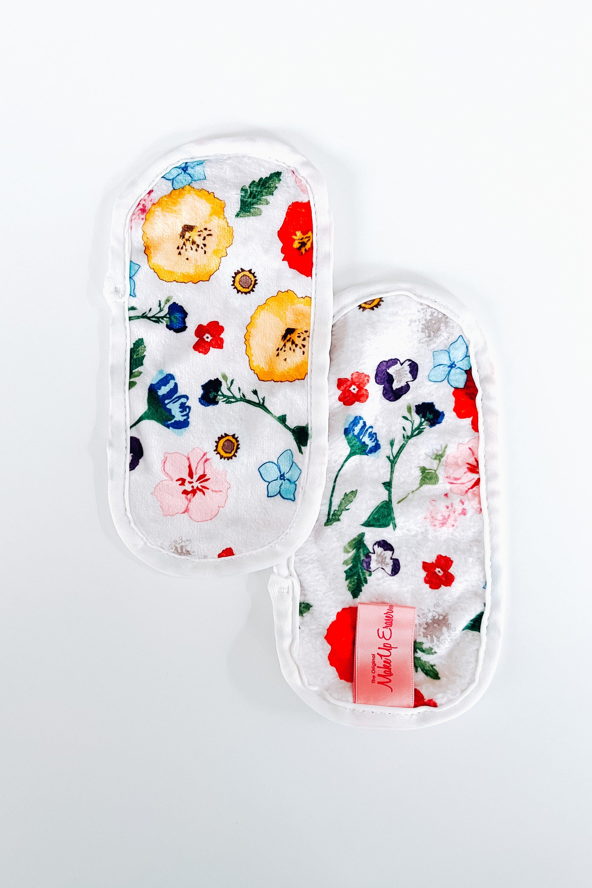 Pair of white mini makeup remover cloths decorated with colorful wildflower prints and a pink branded tag on one side