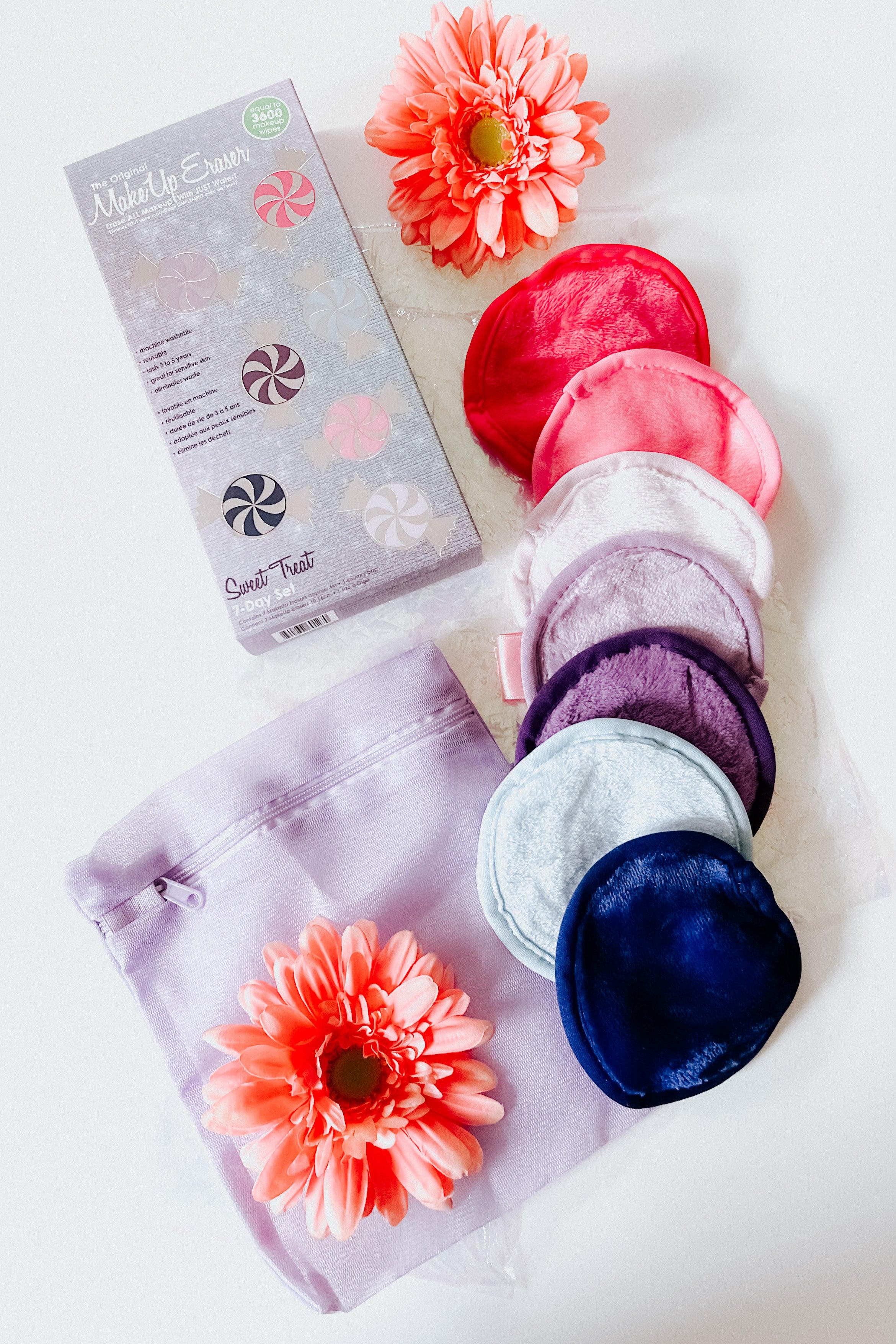Seven soft reusable makeup remover pads in pink, purple, and blue tones with a lavender travel pouch and coral flowers