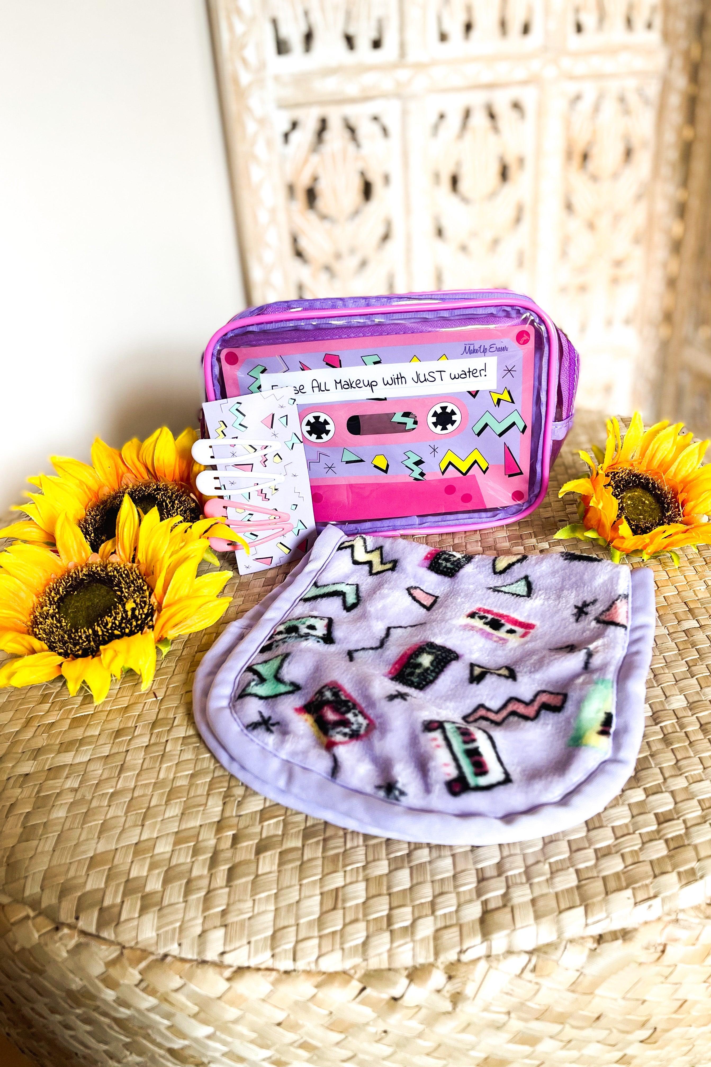 Purple plush makeup remover cloth featuring retro cassette and geometric patterns with bright sunflower accents and a clear pink pouch